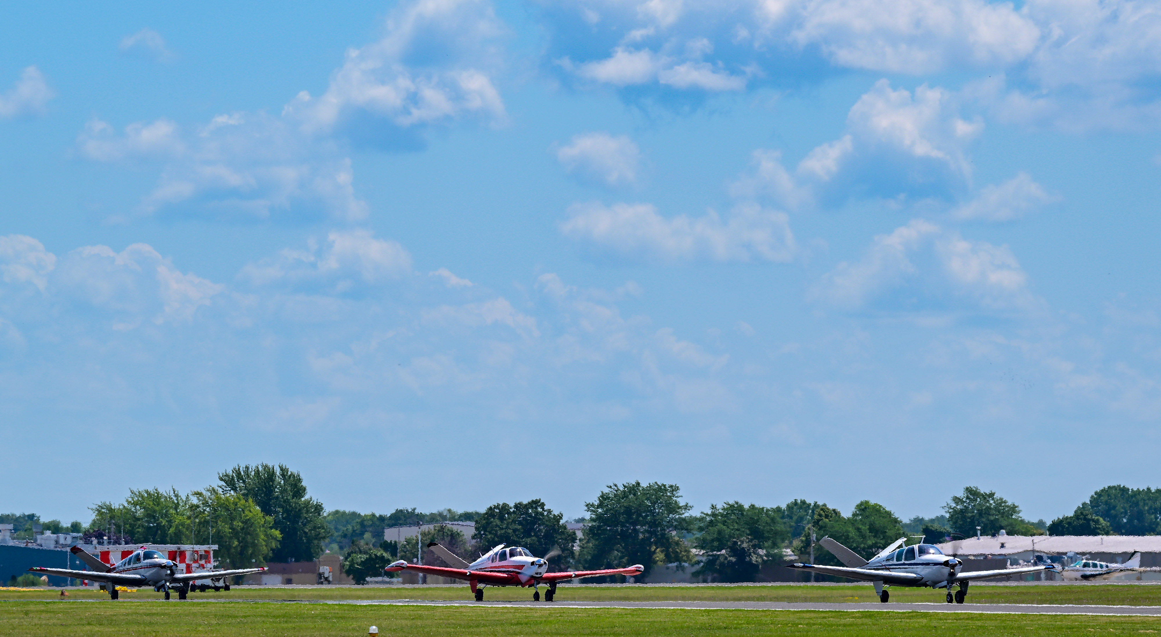 V-tail Bonanzas taxi near Runway 27 after a mass arrival for EAA AirVenture July 23, 2022. Photo by David Tulis.