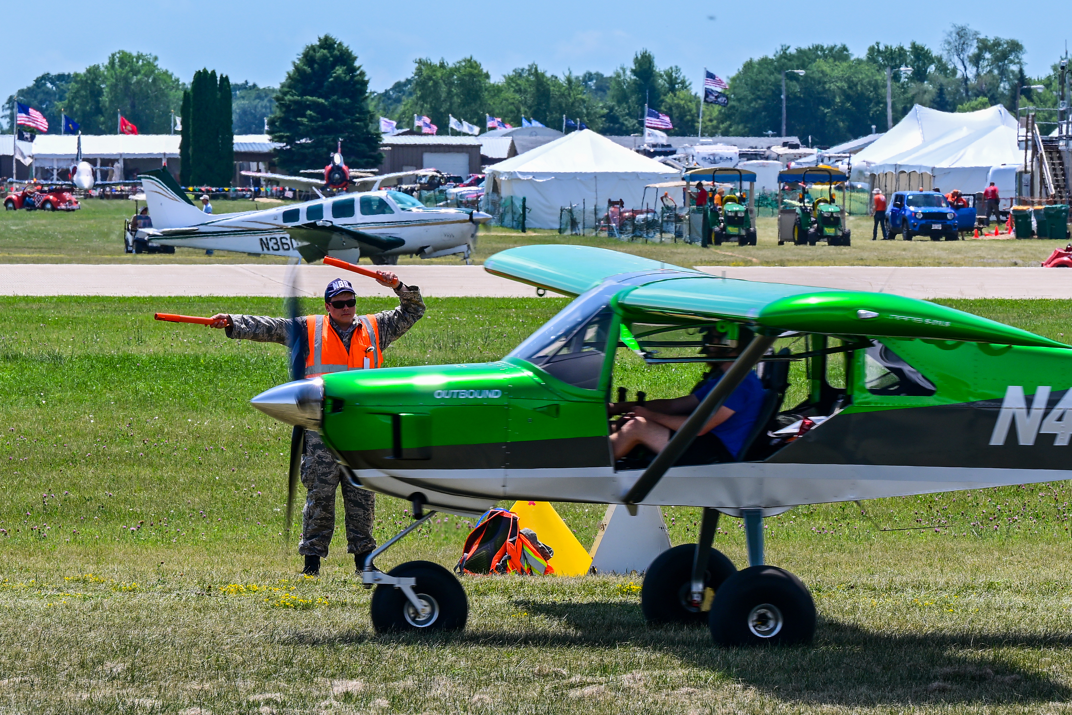 A volunteer lineman directs traffic near the North 40 parking area as early arrivals taxi to their parking destination during EAA AirVenture July 23, 2022. Photo by David Tulis.