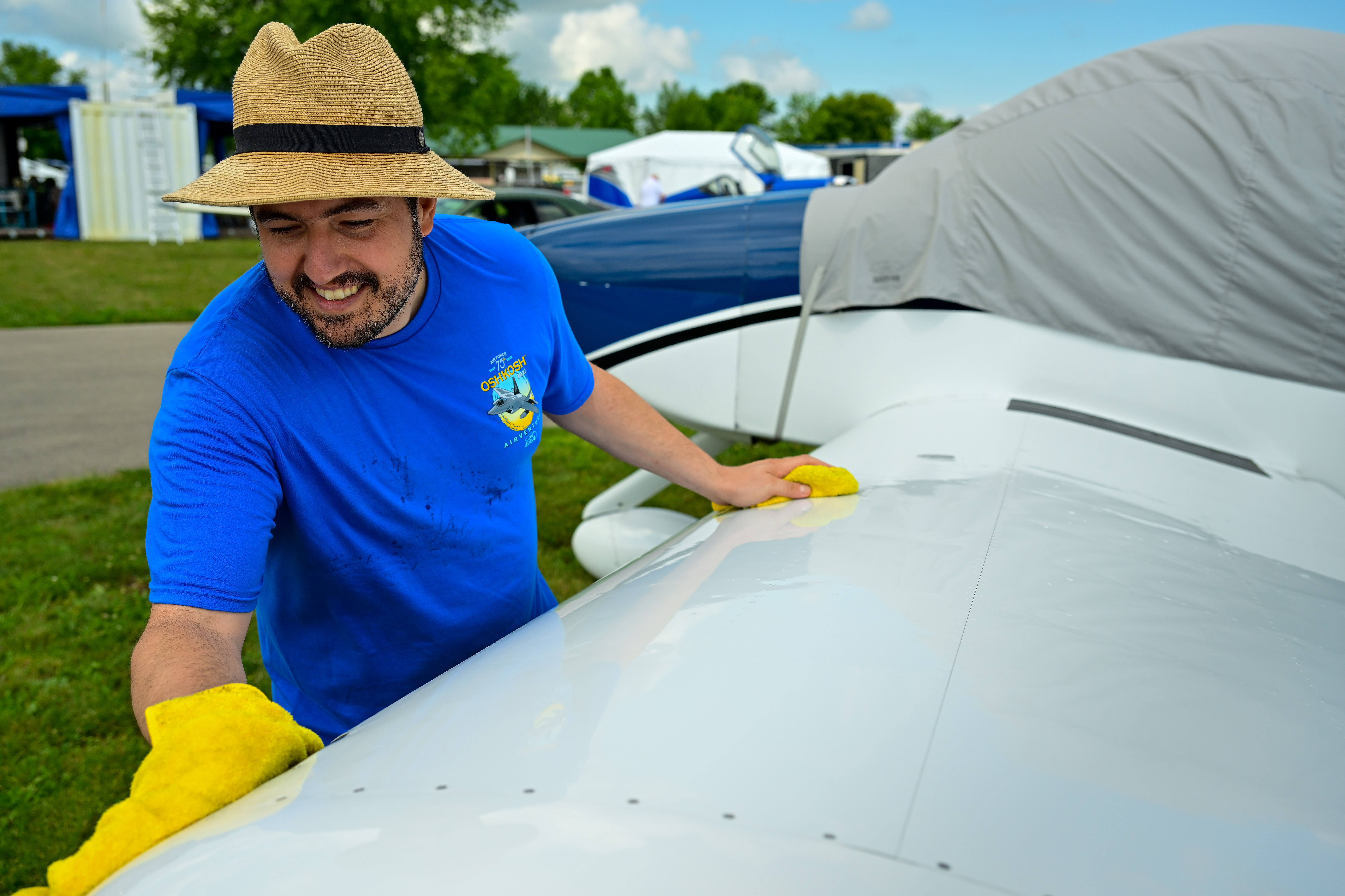 Van’s Aircraft’s Bernardo Malfitano wipes down an aircraft at the manufacturer’s display during EAA AirVenture July 24, 2022. Van’s is celebrating a fiftieth anniversary. Photo by David Tulis.
