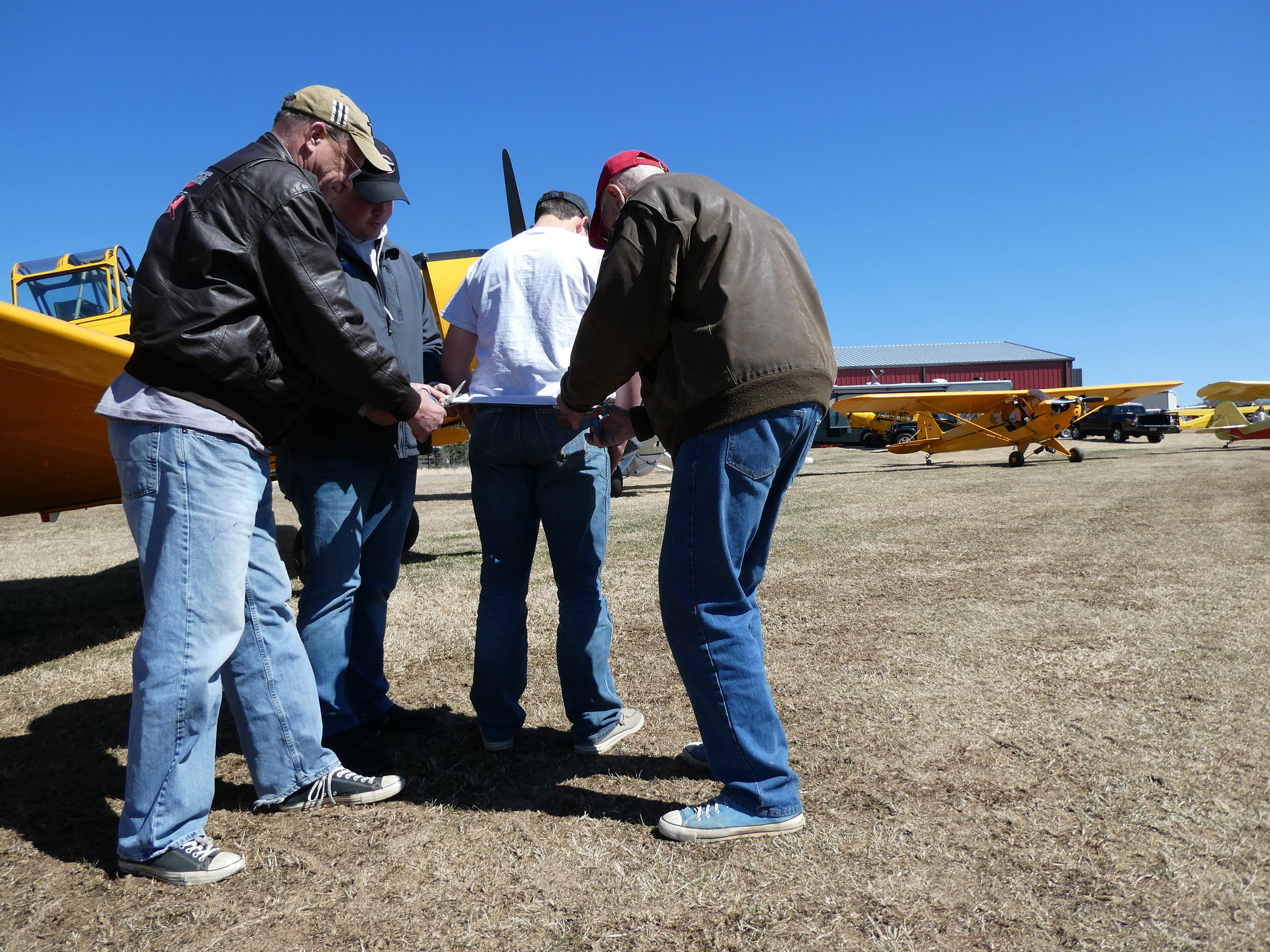 Alan Miller, Jacob Gates, and Harry Ballance cut James Frank’s shirttail after he soloed four airplanes on his sixteenth birthday. Photo by Cayla McLeod.  