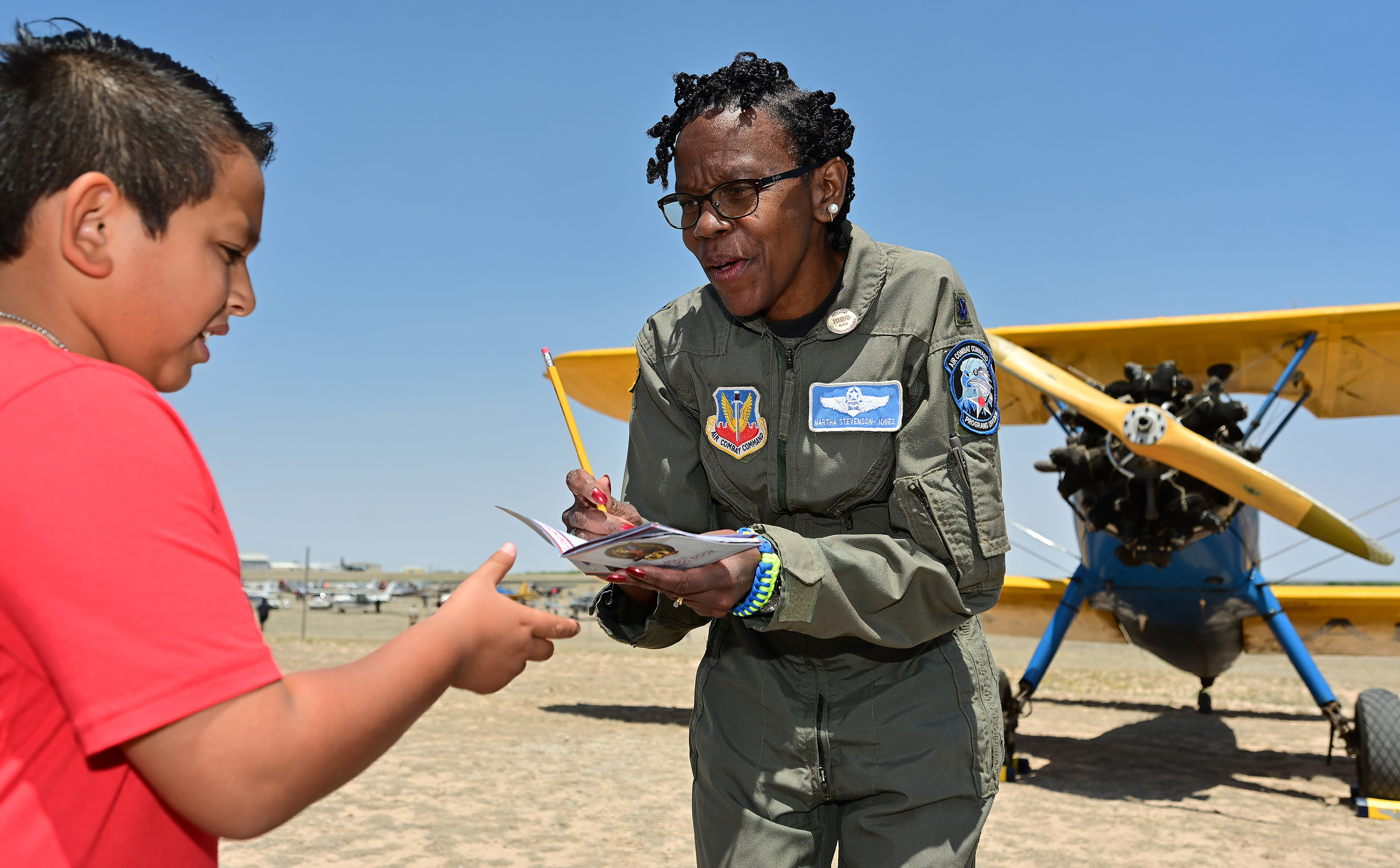 Martha Stevenson-Jones signs an autograph near a Boeing Stearman during a Women Airforce Service Pilots celebration. Photo by David Tulis.