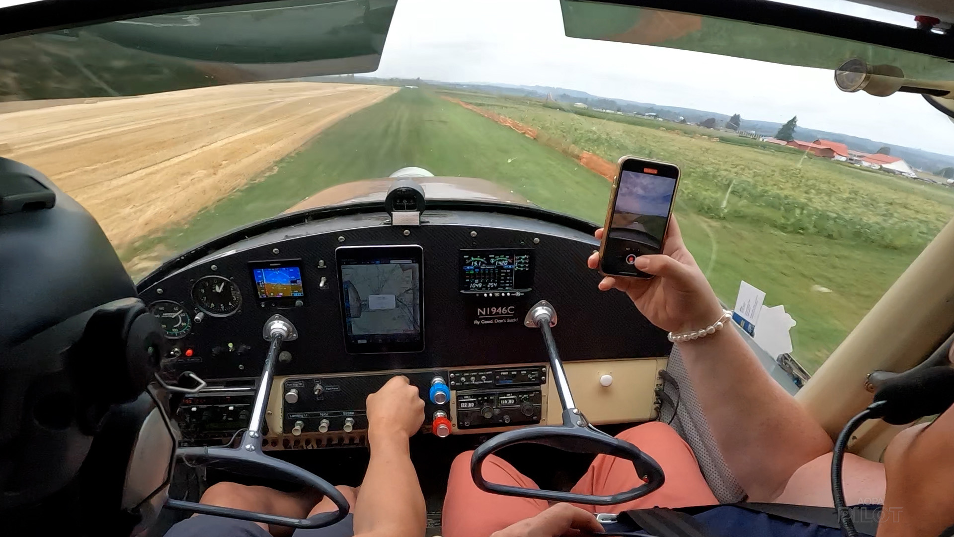 Pilot Teagan LaPointe prepares to touch down on the grass strip at Chapman Farms. Sierra Harrop, right, takes cellphone video. Image by Sierra Harrop.