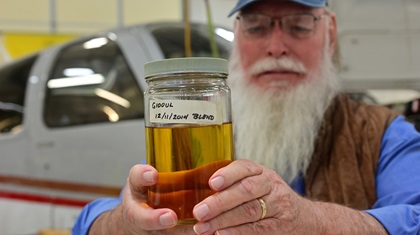 General Aviation Modifications Inc. cofounder George Braly holds a sample of the unleaded fuel that the FAA has approved for use in every airplane engine with a spark ignition system. Photo by David Tulis. 