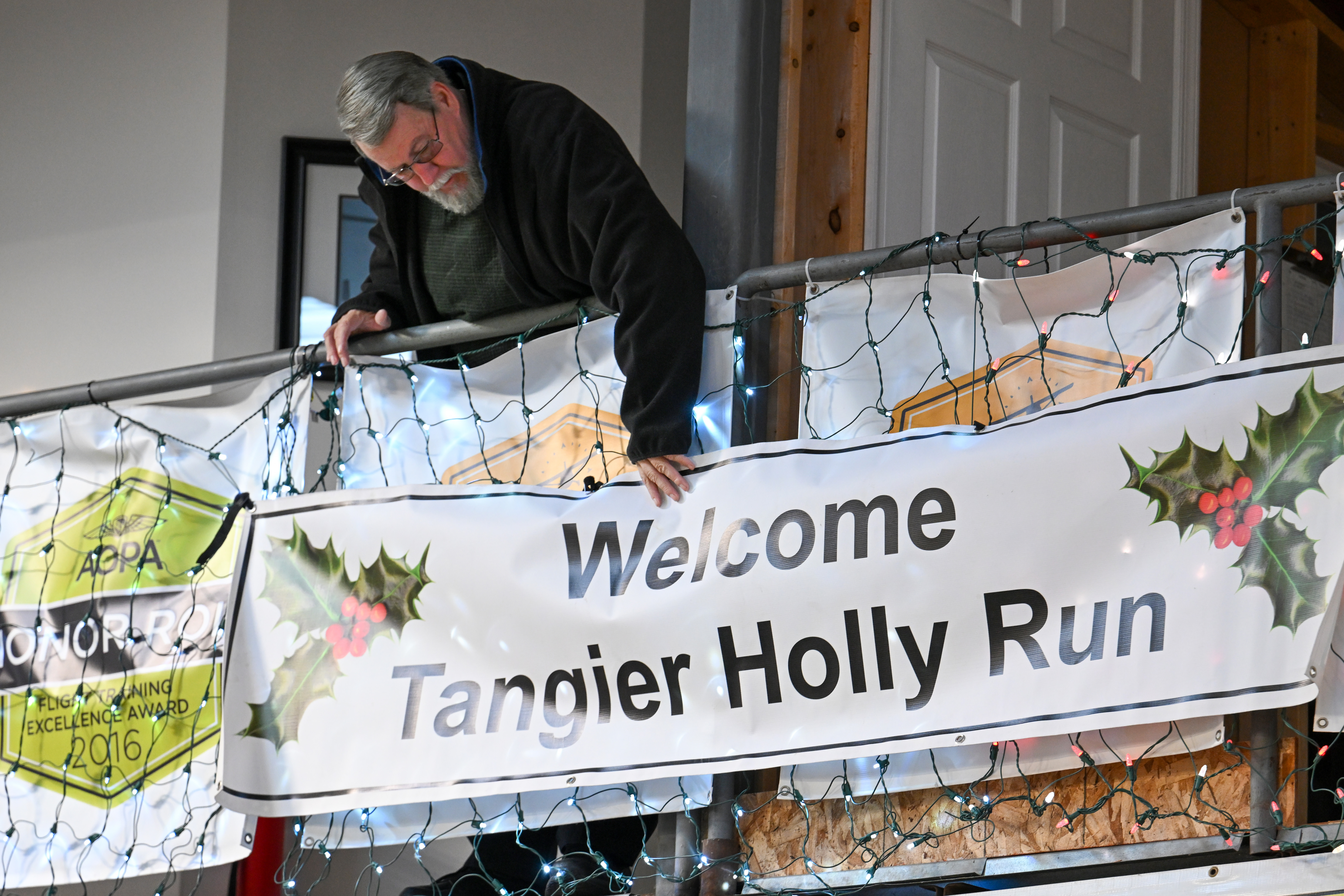 AOPA Airport Support Network volunteer Thomas Kemp adjusts a sign at Bay Bridge Airport in Stevensville, Maryland, for the annual Holly Run fly-out to Tangier Island in the Chesapeake Bay. Photo by David Tulis.