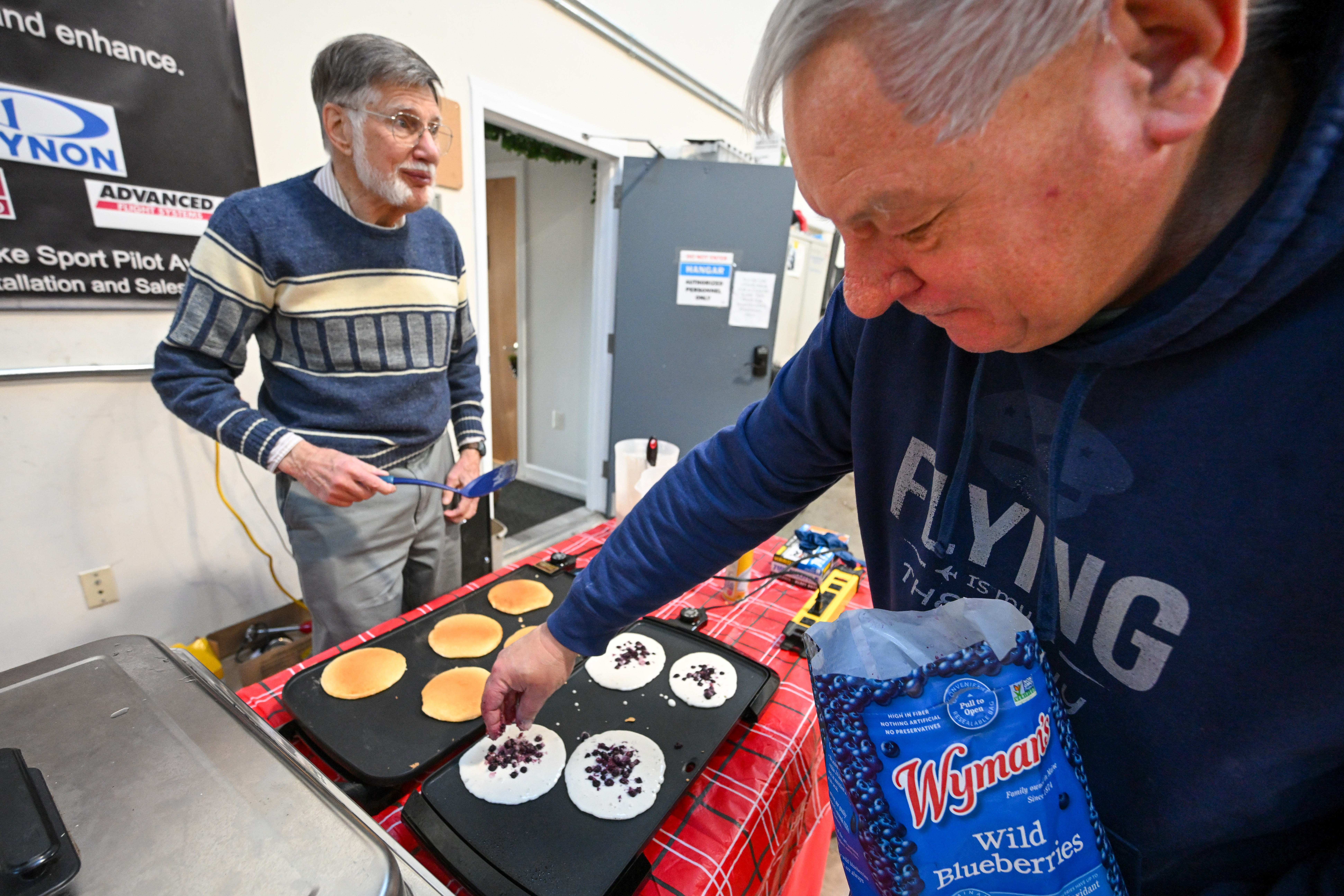 Tony Riggs and Keith Terpil prepare pancakes to fuel pilots before the fly-out. Photo by David Tulis.