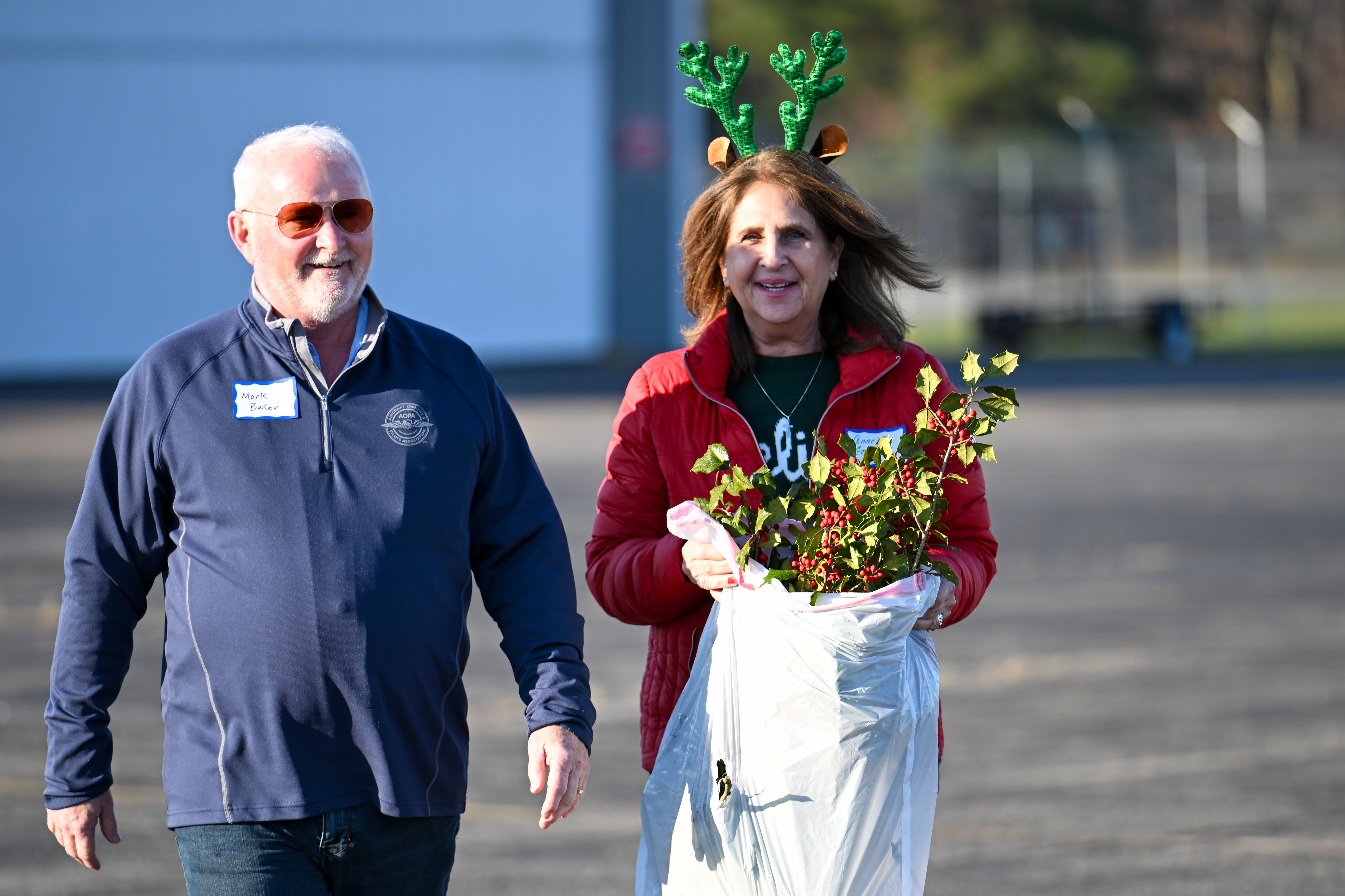 AOPA Pilot Information Center Medical Certification Specialist Annette Garrisi and AOPA President Mark Baker carry a bag of fresh holly branches. Photo by David Tulis.