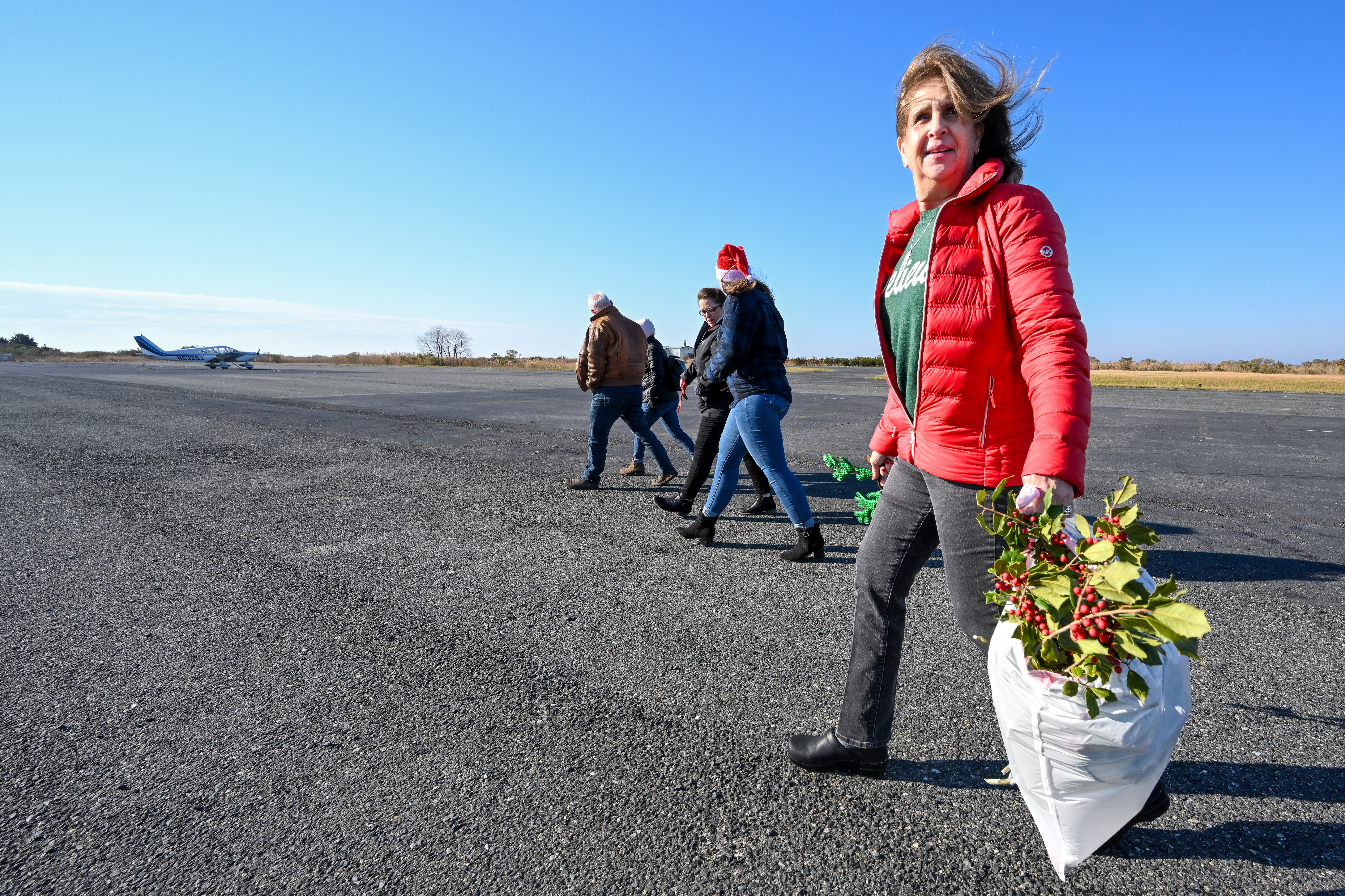 AOPA Pilot Information Center Medical Certification Specialist Annette Garrisi carries a bag of fresh holly branches to the residents of Tangier Island. Photo by David Tulis.