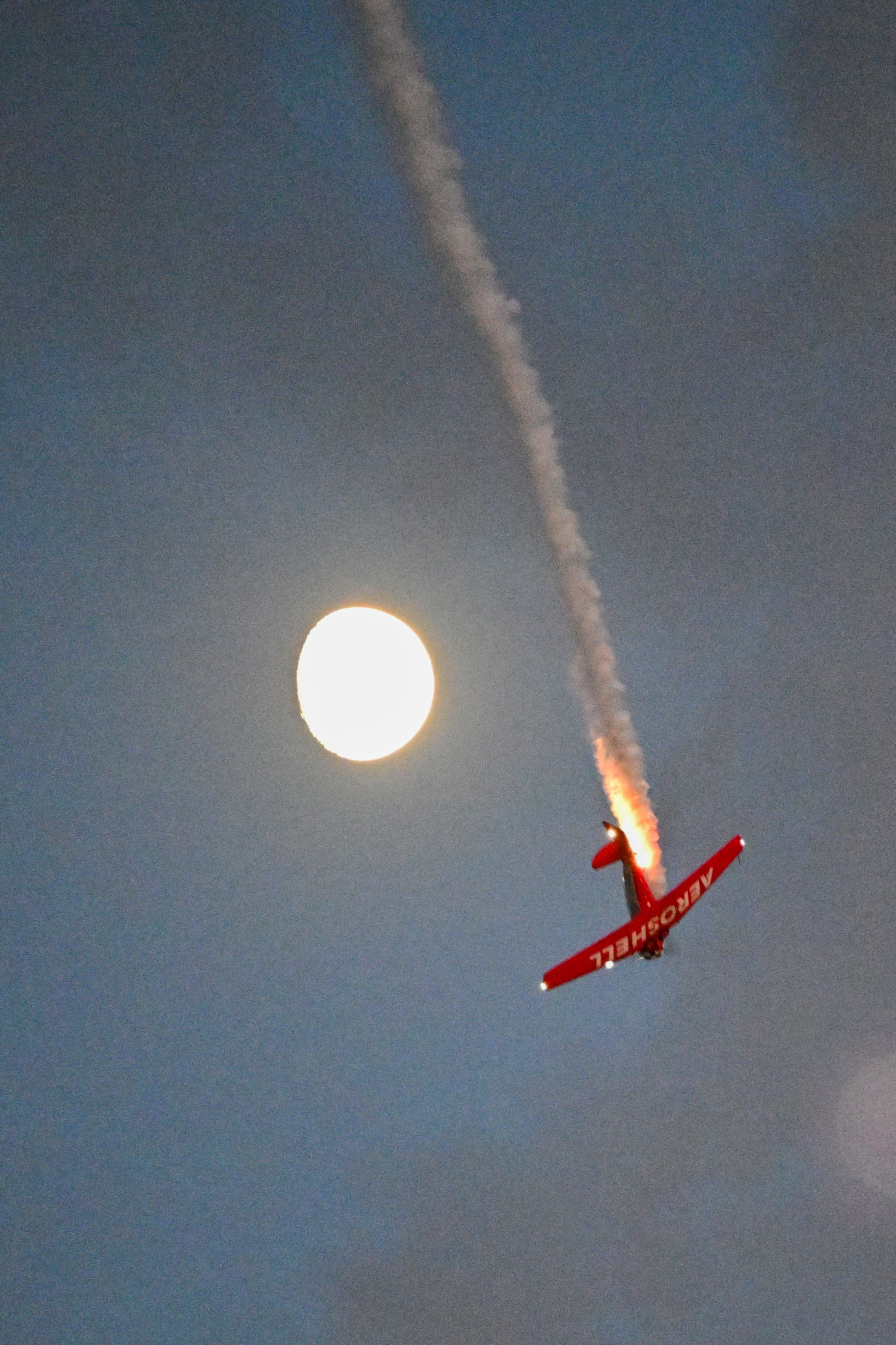 An AeroShell Aerobatic Team pilot passes under the rising moon. Photo by David Tulis.