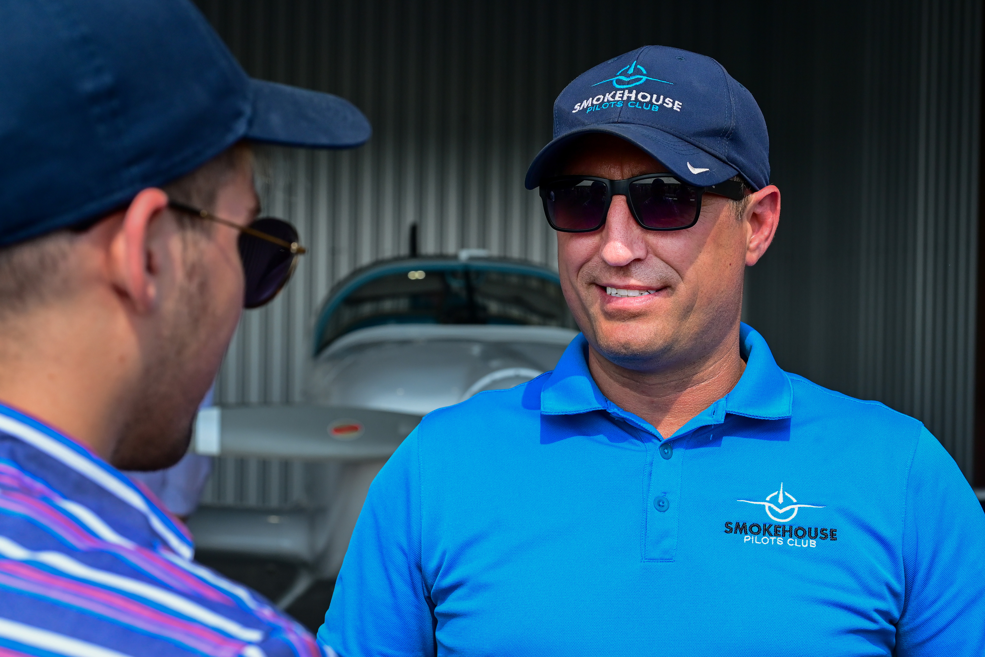 Smokehouse Pilots Club cofounder Gabriel Muller speaks with guests at the social club's annual fly-in and barbecue at Leesburg Executive Airport. The club adopted its name from a since-closed restaurant where pilots, aviation students, instructors, and aircraft owners met to discuss and encourage local aviation. Photo by David Tulis.