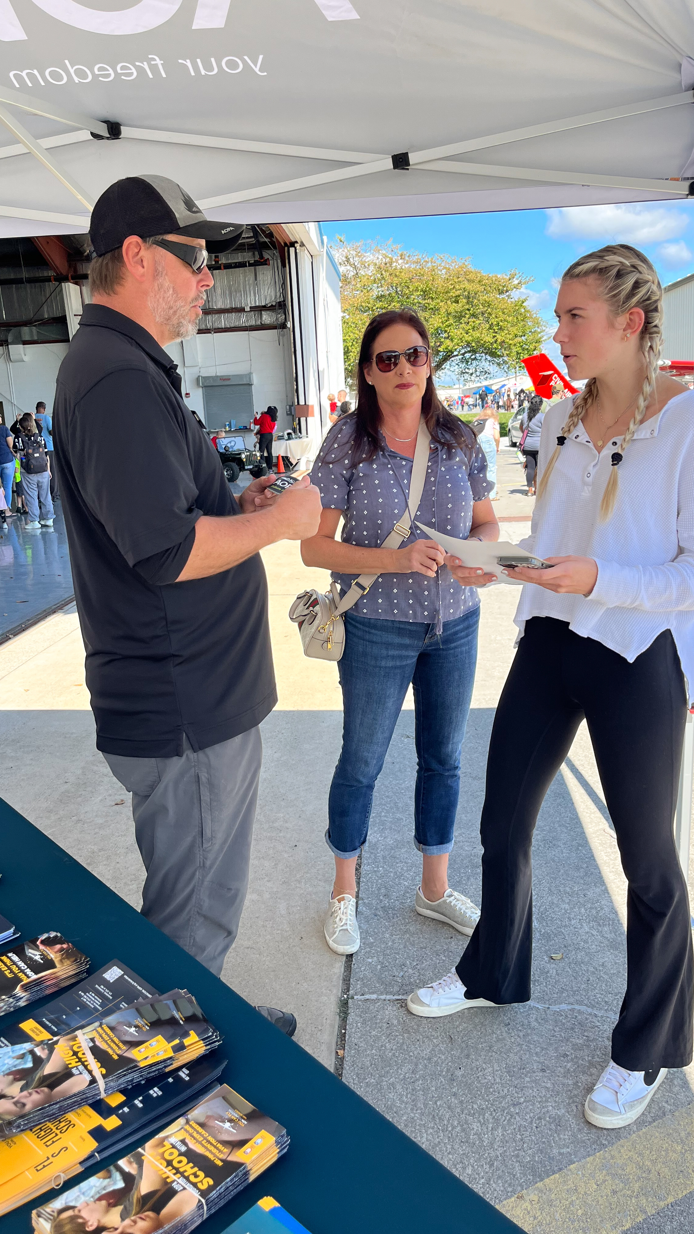 AOPA’s Dan Justman explains flight training scholarships to Natalia and Danea Ross. Photo by Sylvia Horne.
