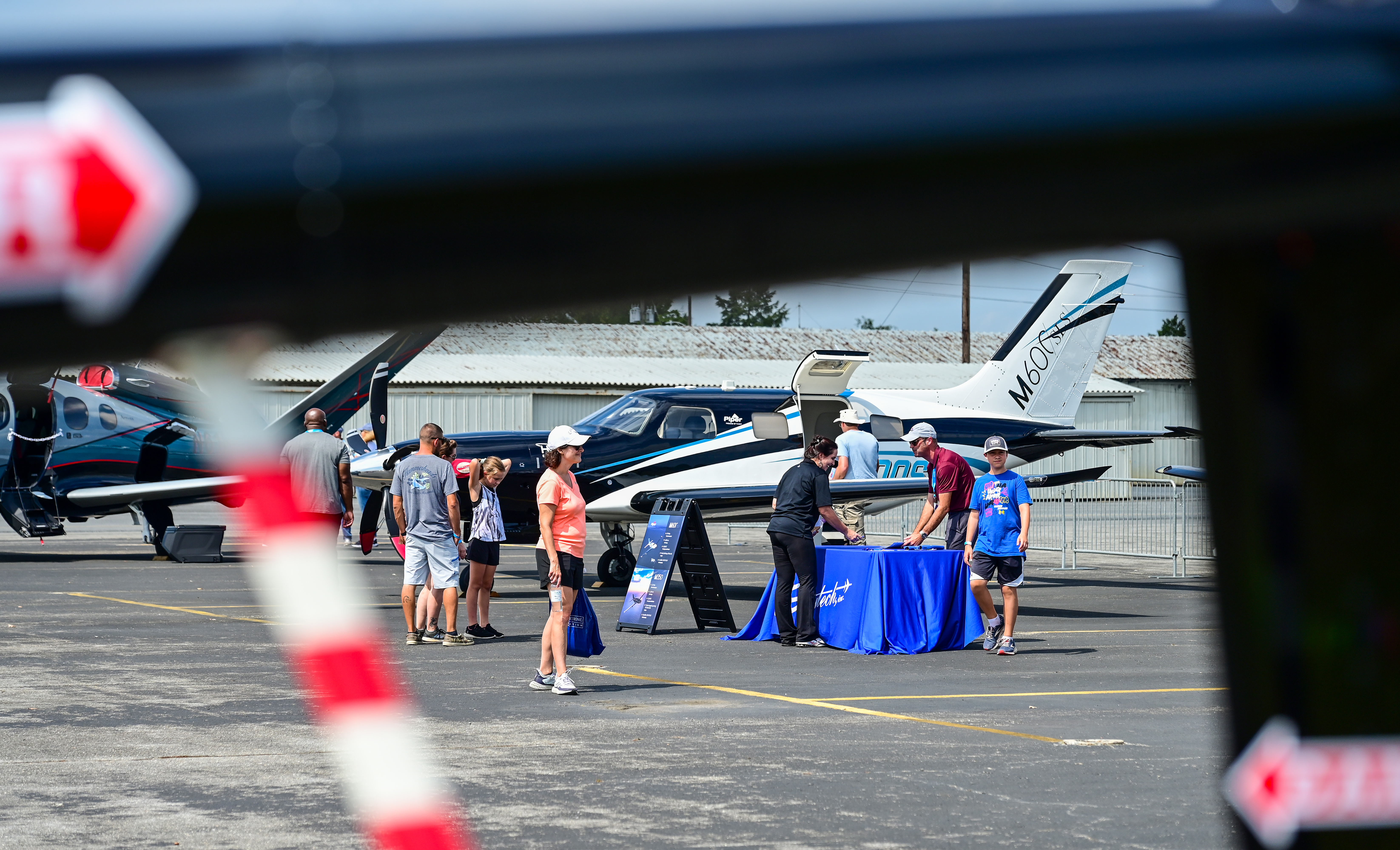 A Piper M600 at the static display is framed by the tail boom of a Robinson helicopter. Photo by David Tulis. 