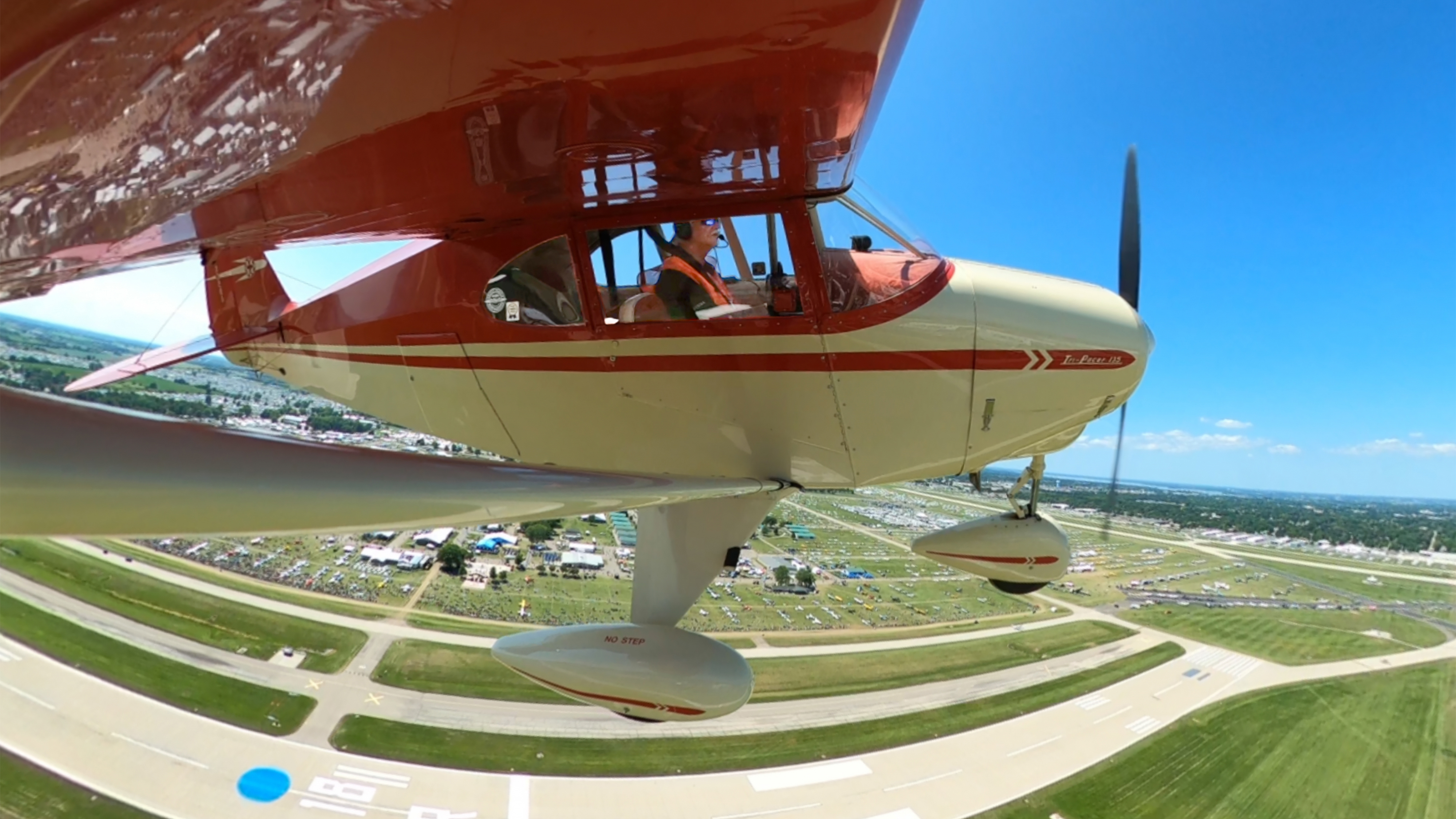 A museum-restored 1953 Piper Tri-Pacer turns right during a Vintage in Review aerial parade lap for 12 pilots and their historic aircraft who participated in the Thursday afternoon airshow at EAA AirVenture in Oshkosh, Wisconsin, July 25. Photo by David Tulis.