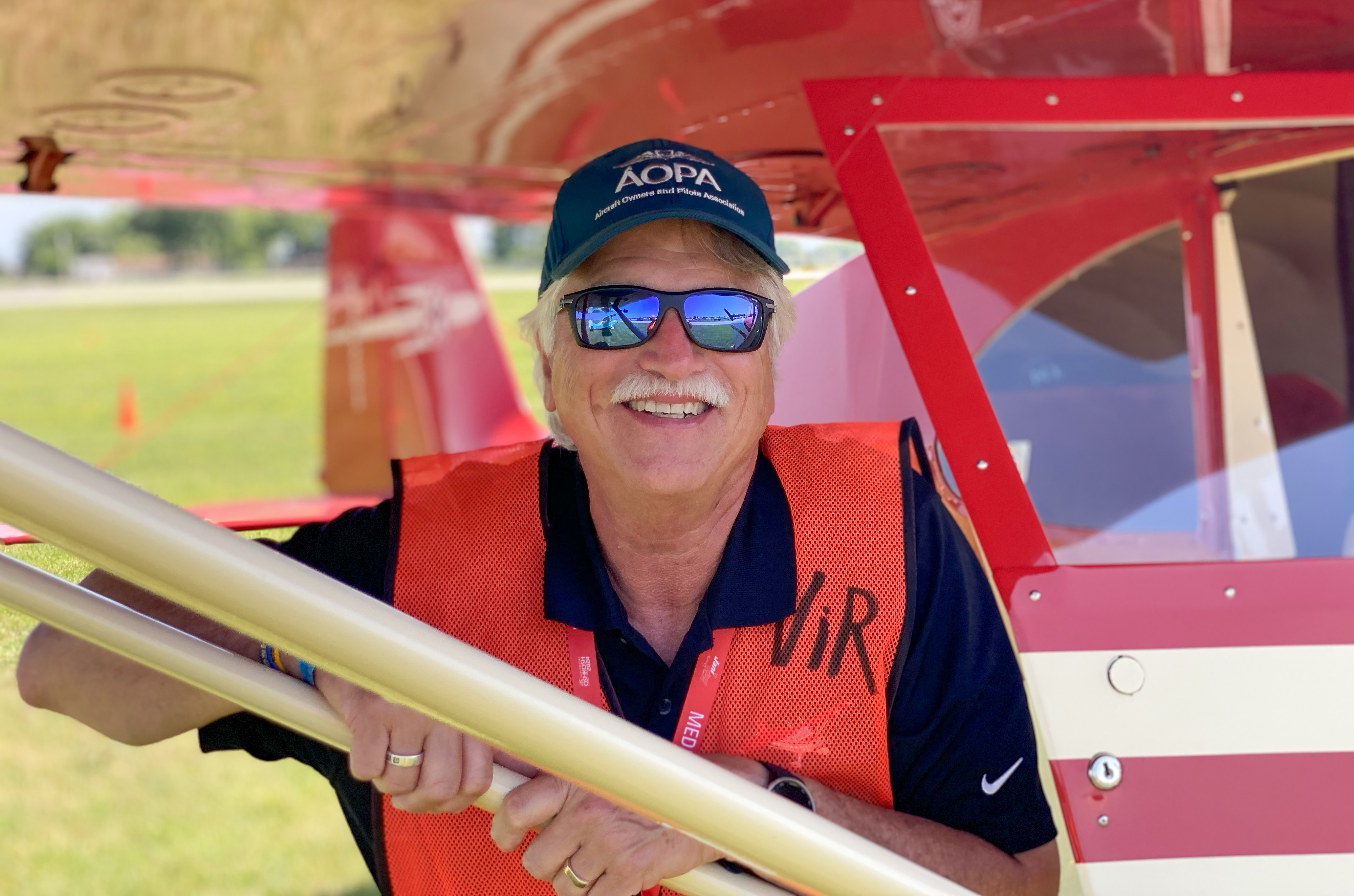 With an orange safety vest on, Vintage in Review flyover pilot David Tulis is ready to participate in the July 25 afternoon airshow during EAA AirVenture. Photo courtesy of Jennifer Payne, EAA.