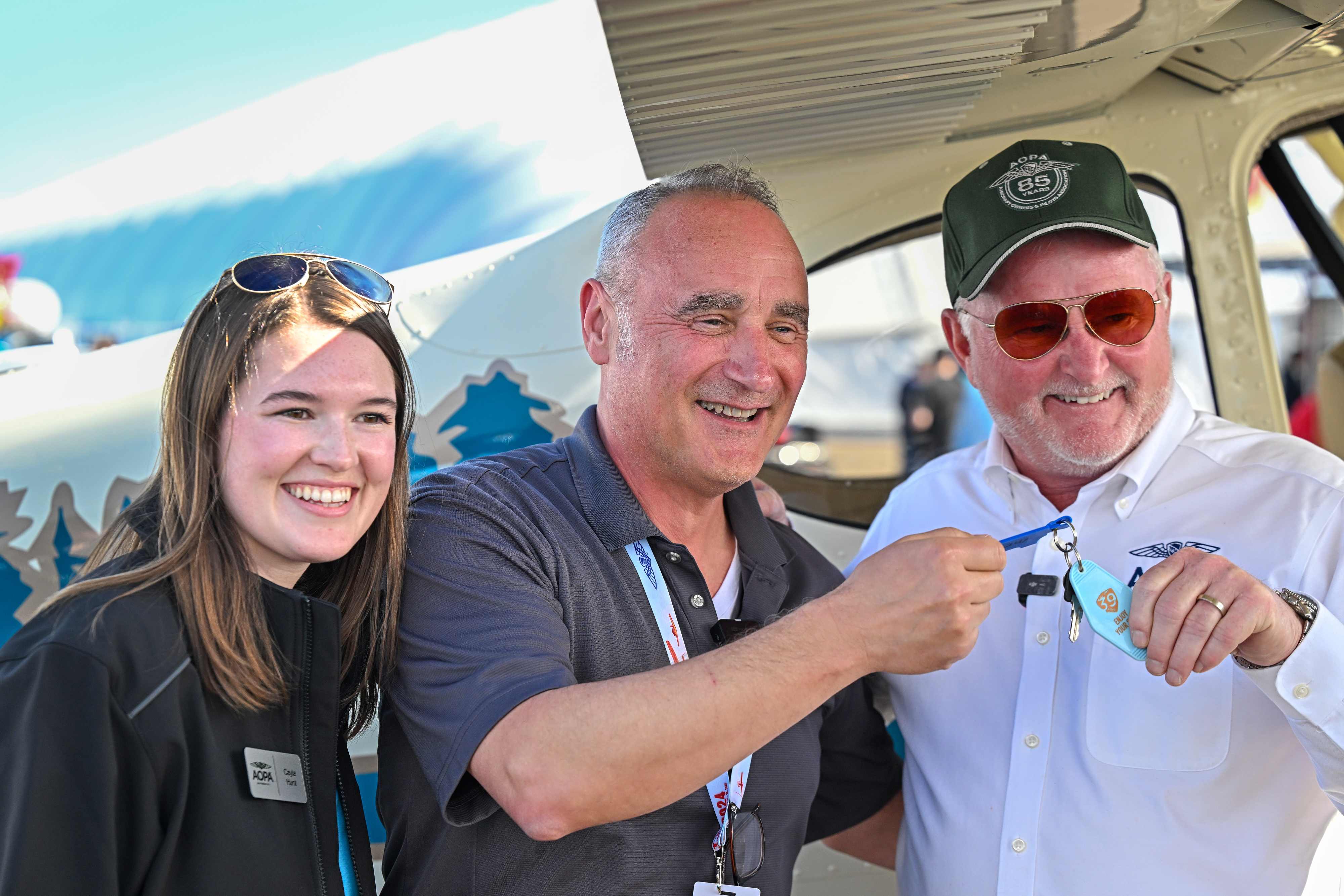 Southwest Airlines pilot Cliff Gurske takes the keys from AOPA President Mark Baker and AOPA Sweepstakes Cessna 170B project manager Cayla Hunt on February 17. Photo by David Tulis.