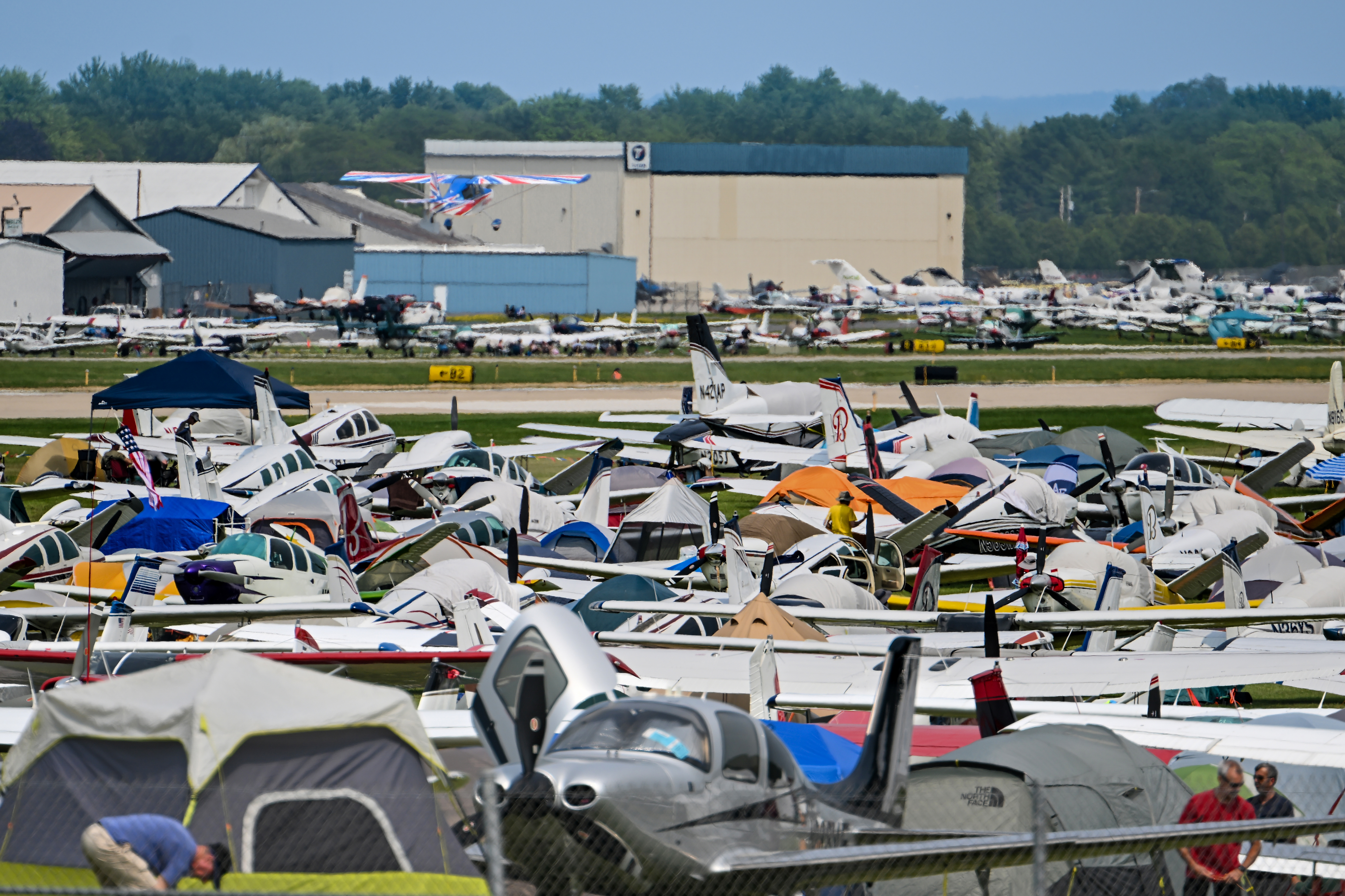 The North 40 camping area is crowded with pilots and aircraft as an American Champion Aircraft Decathlon takes off on July 21. Photo by David Tulis.