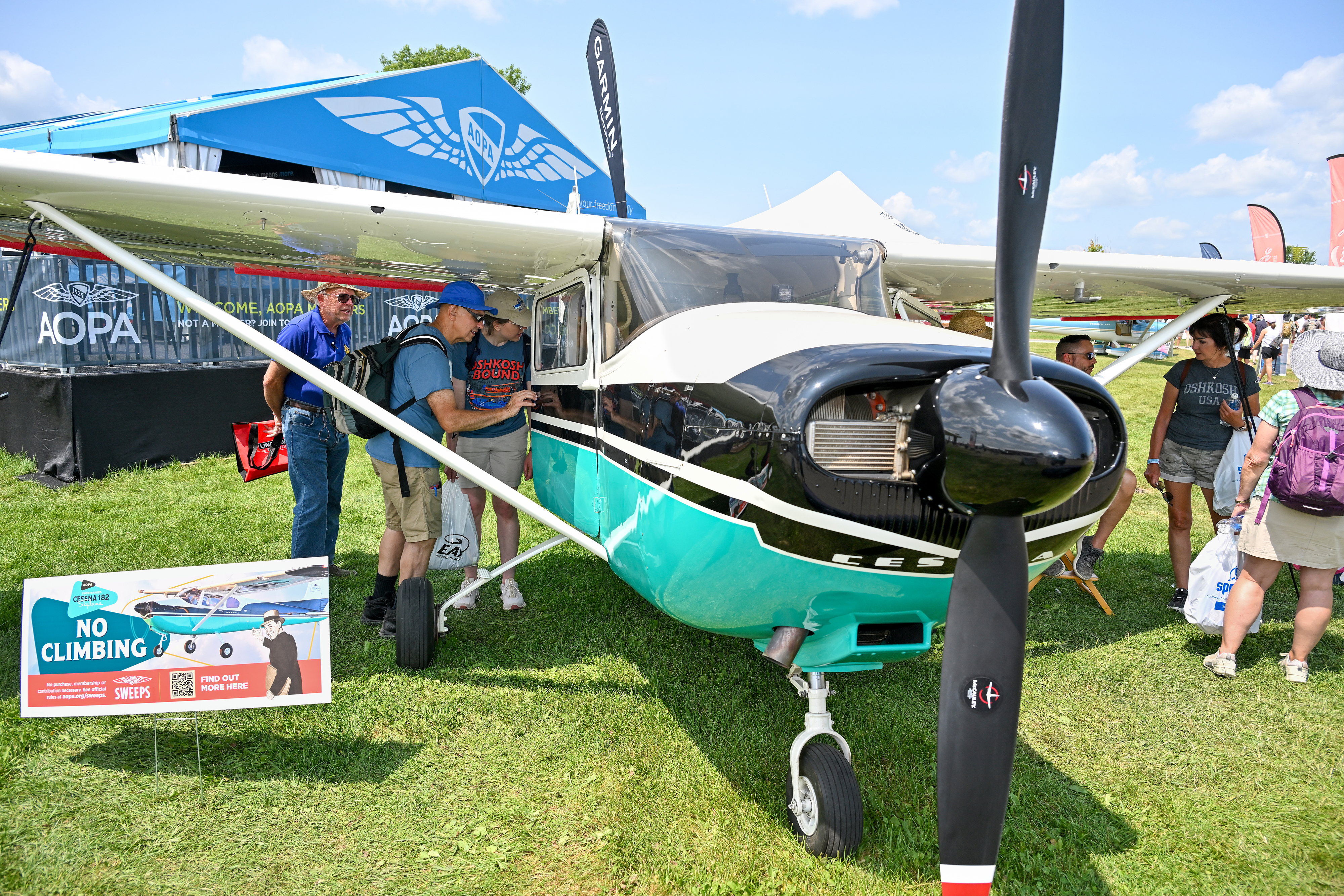 Attendees crowd around the AOPA Sweepstakes Cessna 182. Photo by David Tulis.