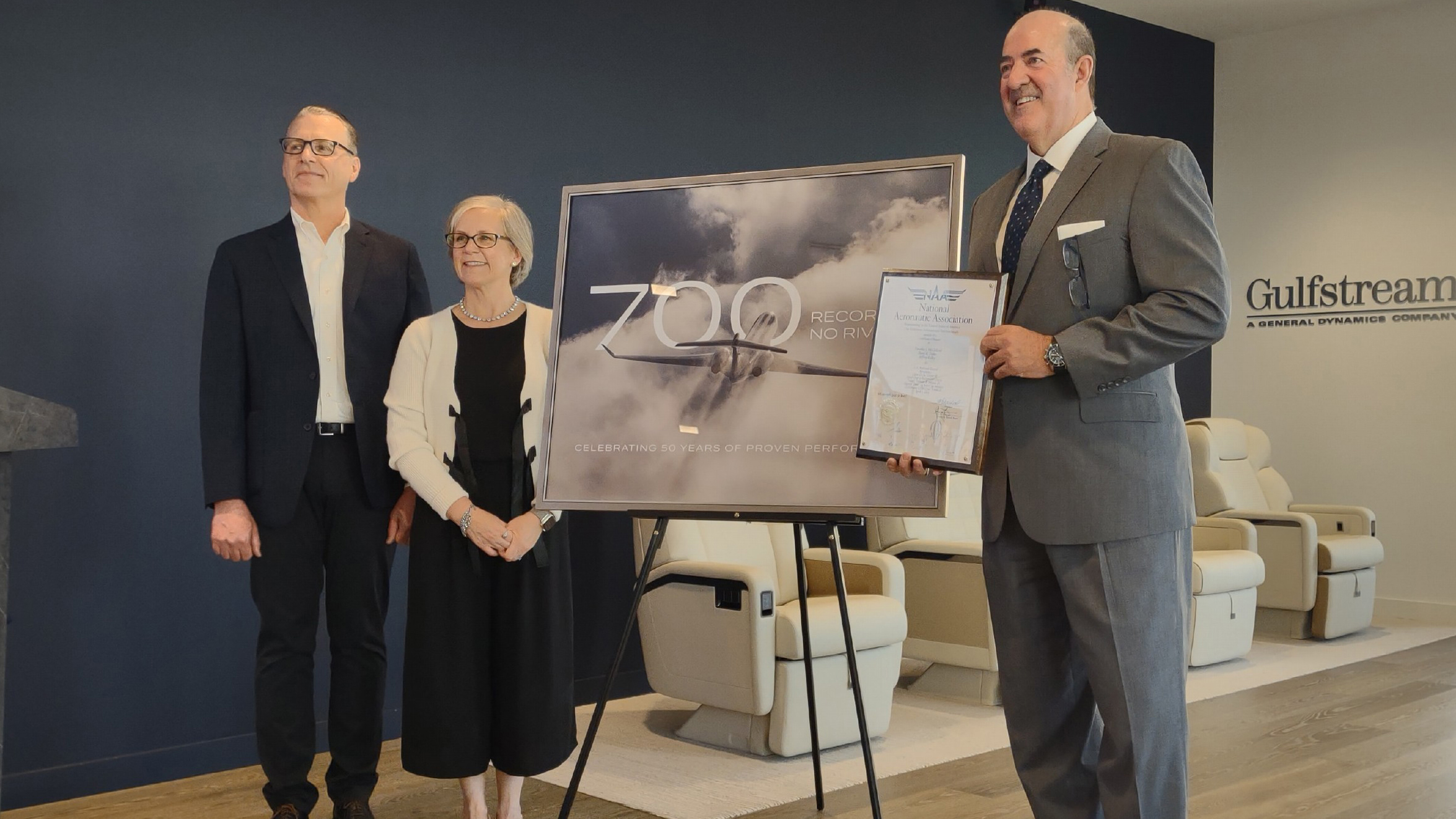 National Aeronautic Association President and CEO Amy Spowart and Senior Vice President of Contest and Records Art Greenfield present Gulfstream President Mark Burns with a plaque commemorating the company’s 700th city-pair speed record. Photo by Jonathan Welsh.
