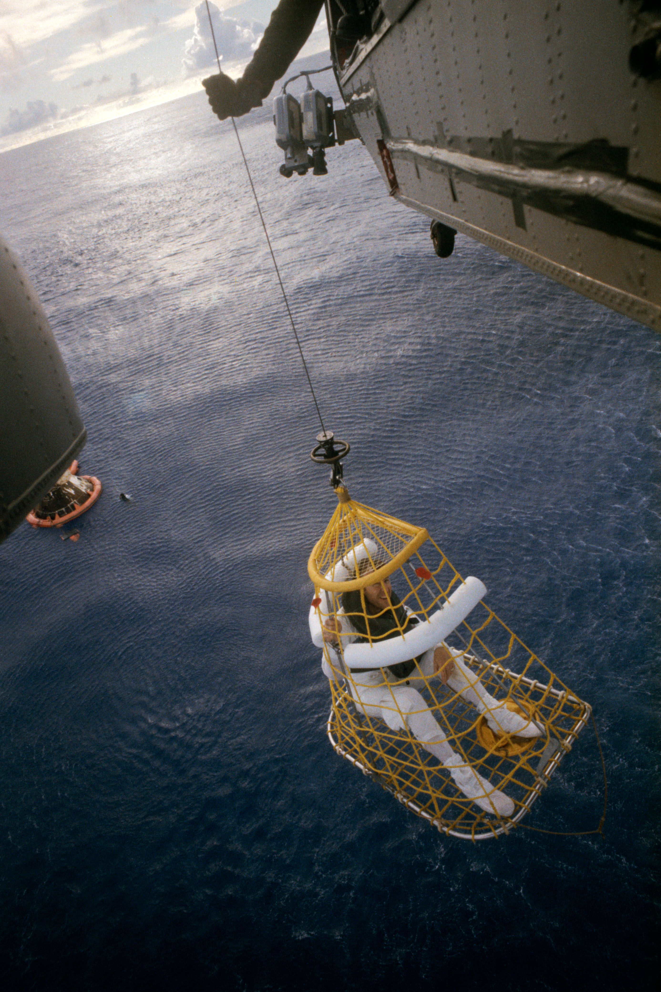 Lovell is hoisted aboard the USS Iwo Jima by a helicopter after a successful splashdown in the South Pacific during the Apollo 13 mission. He was the last of the three crew members to egress the command module, which can be seen in the background. Photo courtesy of NASA. 