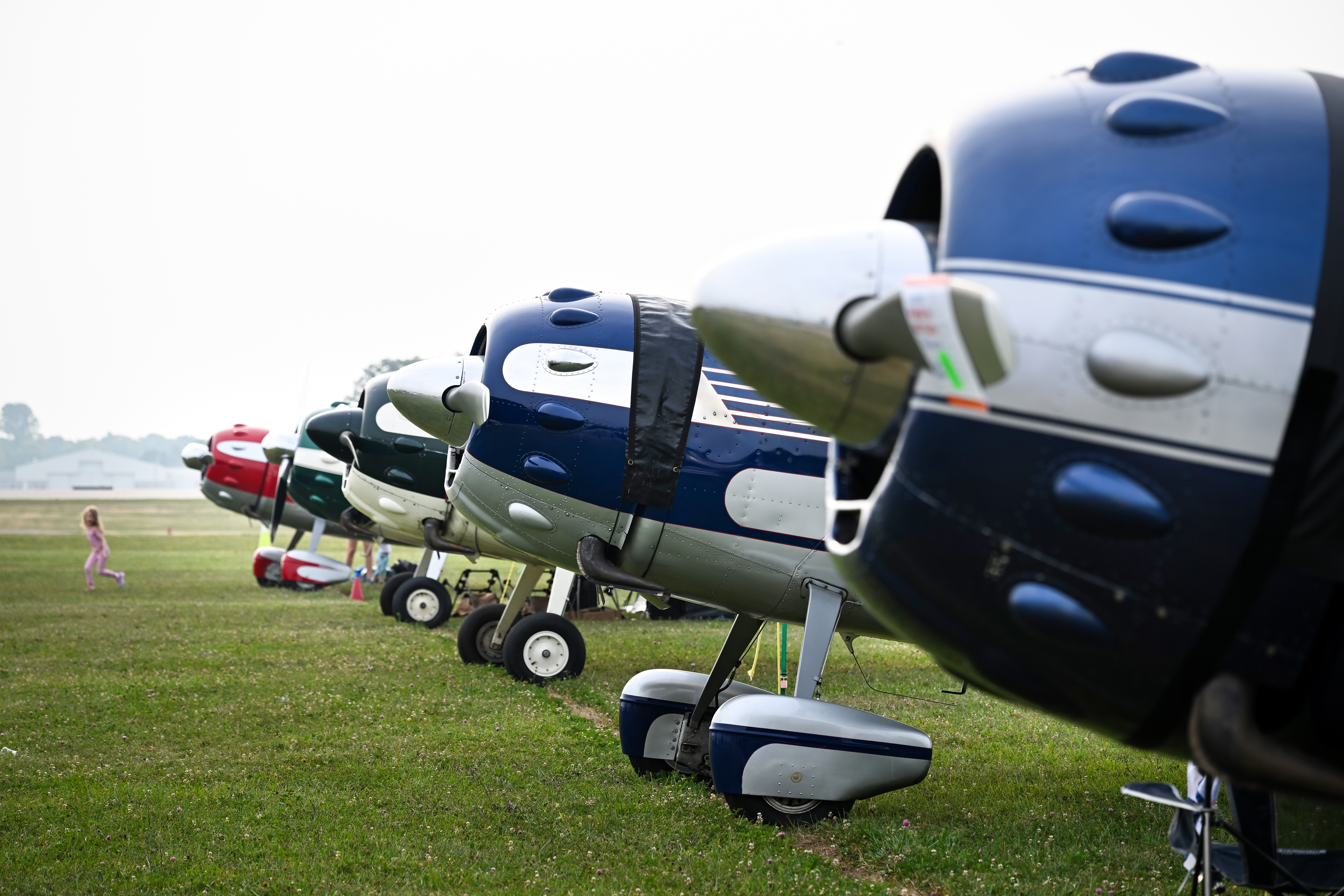 A youth walks past a group of Cessna 195s on the flight line near the vintage camping area. Photo by David Tulis.