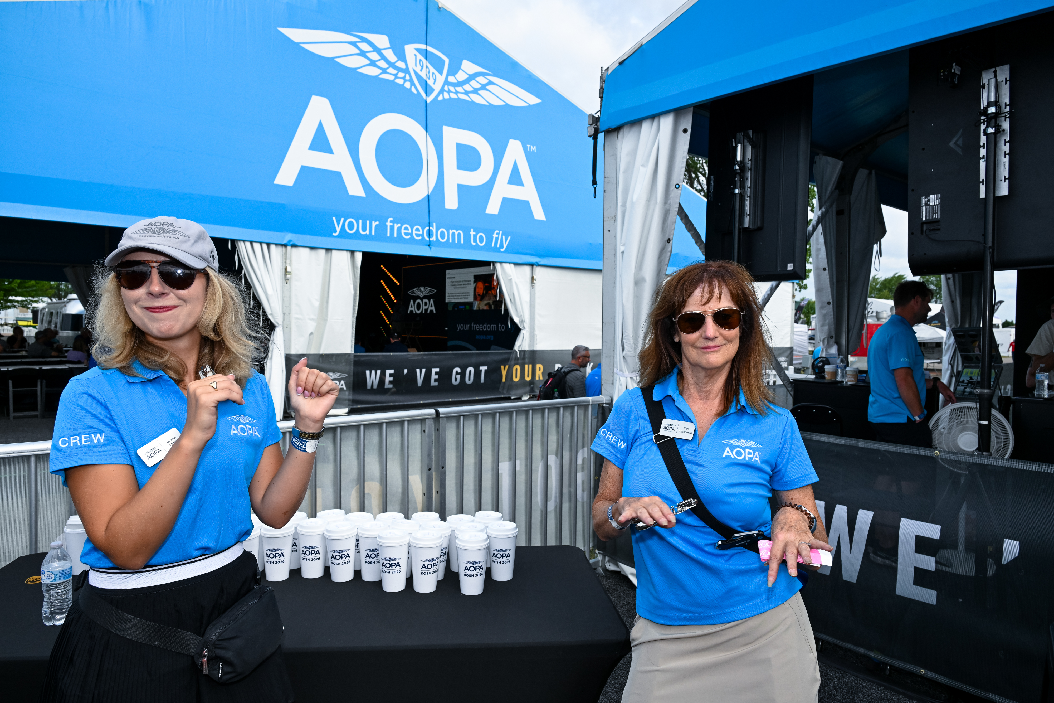 AOPA employees Addison Lomax and Kimberly Trischman get into the AirVenture spirit during a morning coffee break. Photo by David Tulis.