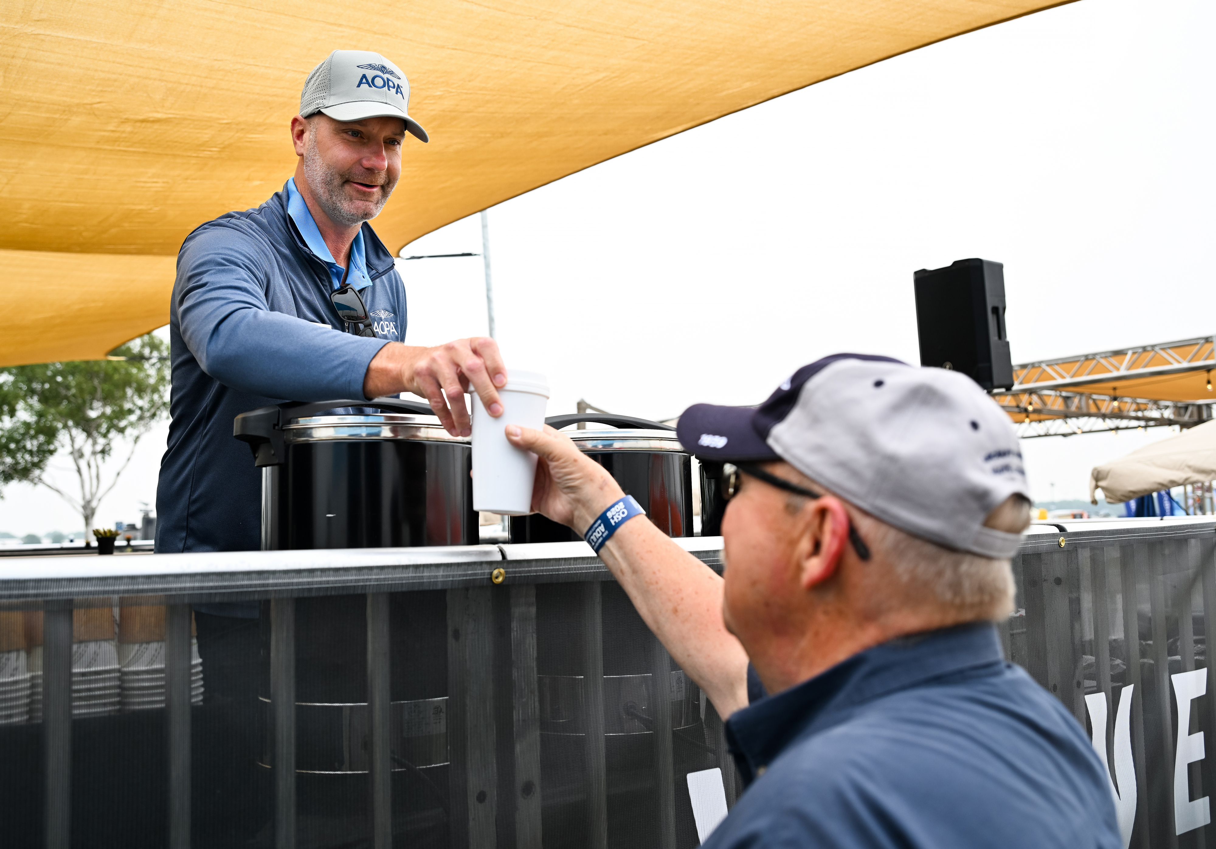 AOPA Board Chair Luke Wippler serves coffee to member Harlin Hawkins during a Morning Brew event at the AOPA campus on July 20. Photo by David Tulis.