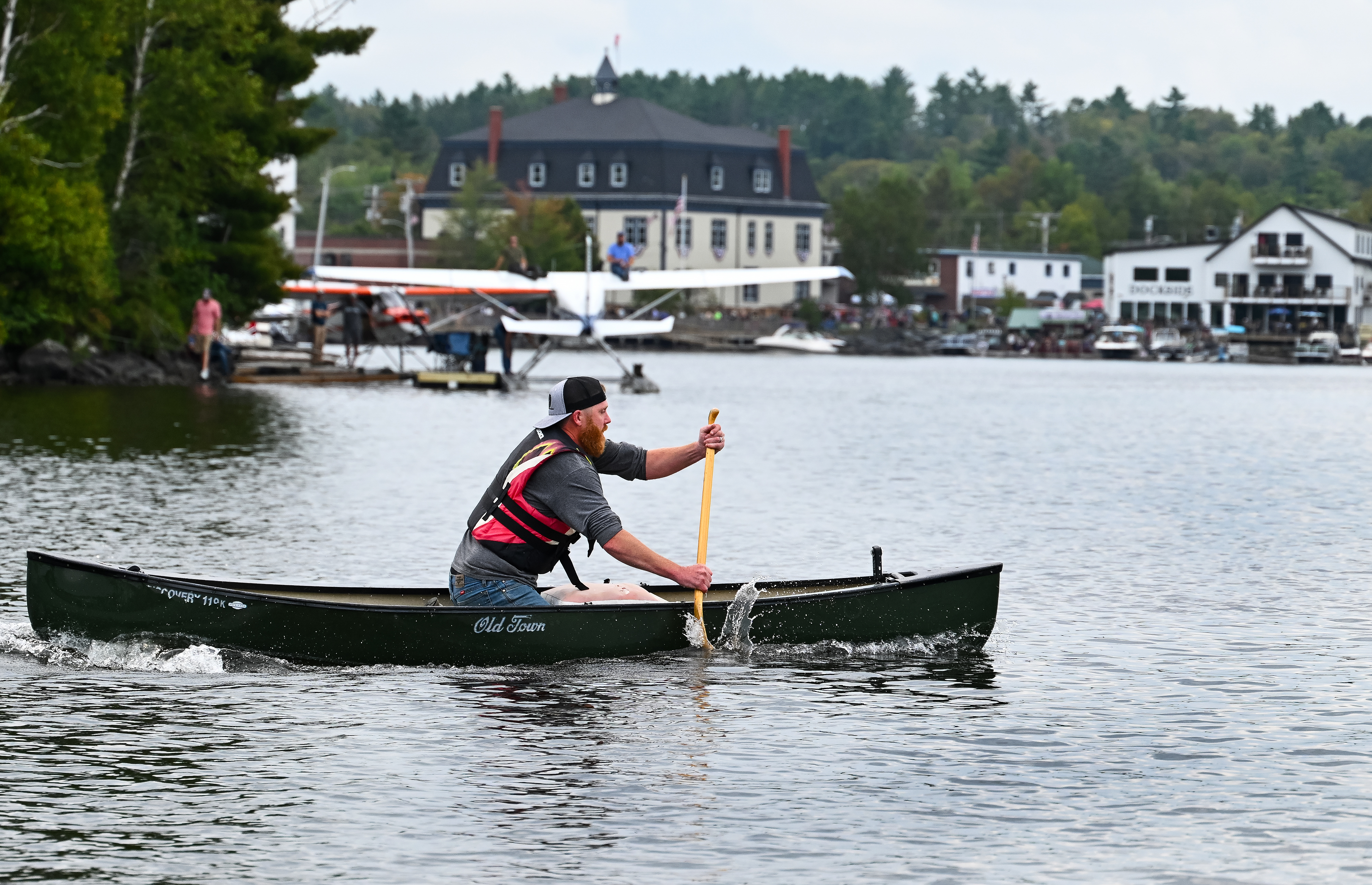 Dustin Dunn paddles a canoe to join up with his father, Tommy, who is simultaneously water taxiing a 1953 Cessna 180 floatplane toward a rendezvous at a Moosehead Lake dock during the timed contest. Photo by David Tulis.