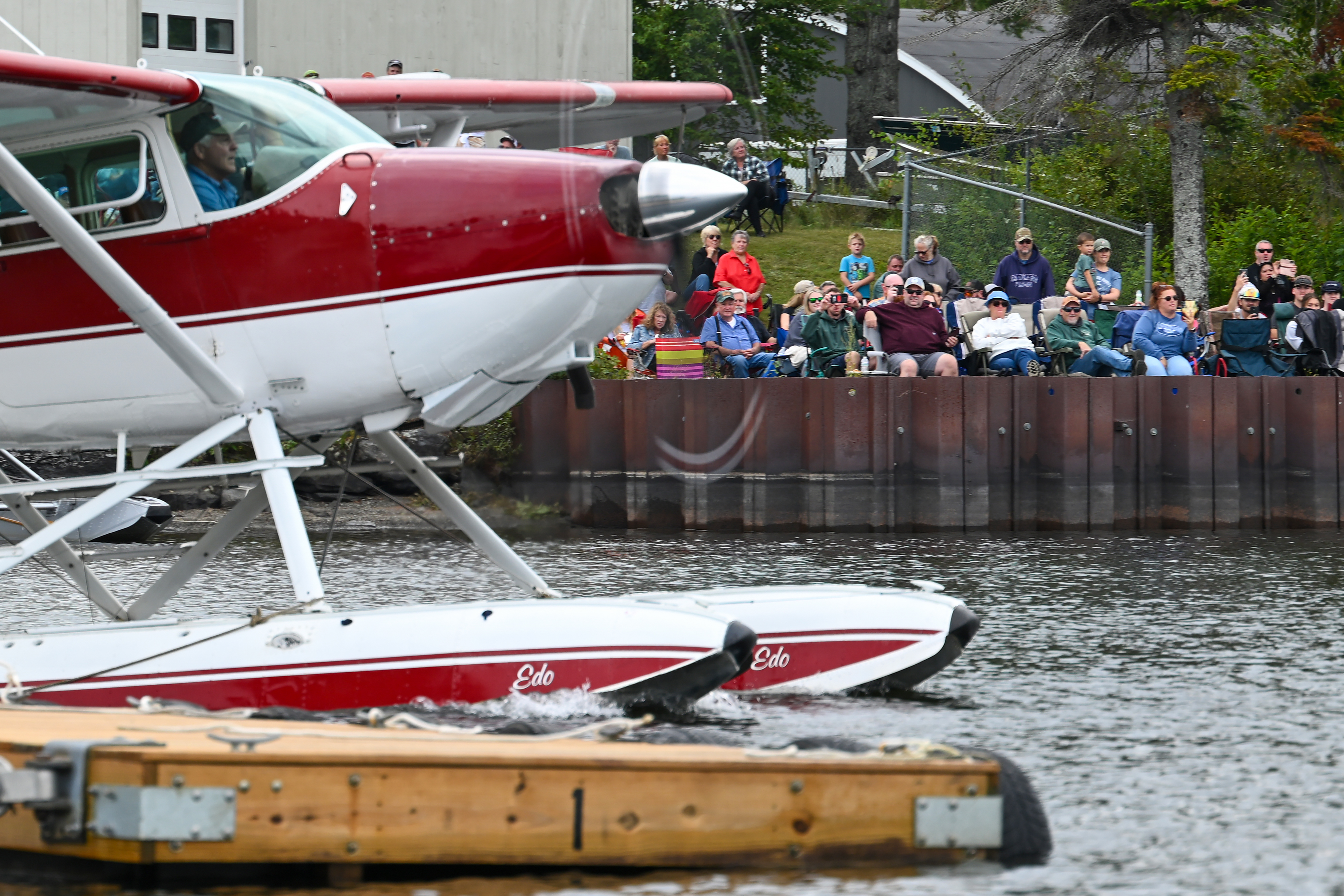 Spectators watch from the shore of Moosehead Lake while Tommy Dunn water taxis a 1953 Cessna 180 on straight EDO floats to a dock where he will meet up with his son, Dustin, who is paddling a canoe toward the rendezvous point. Photo by David Tulis.
