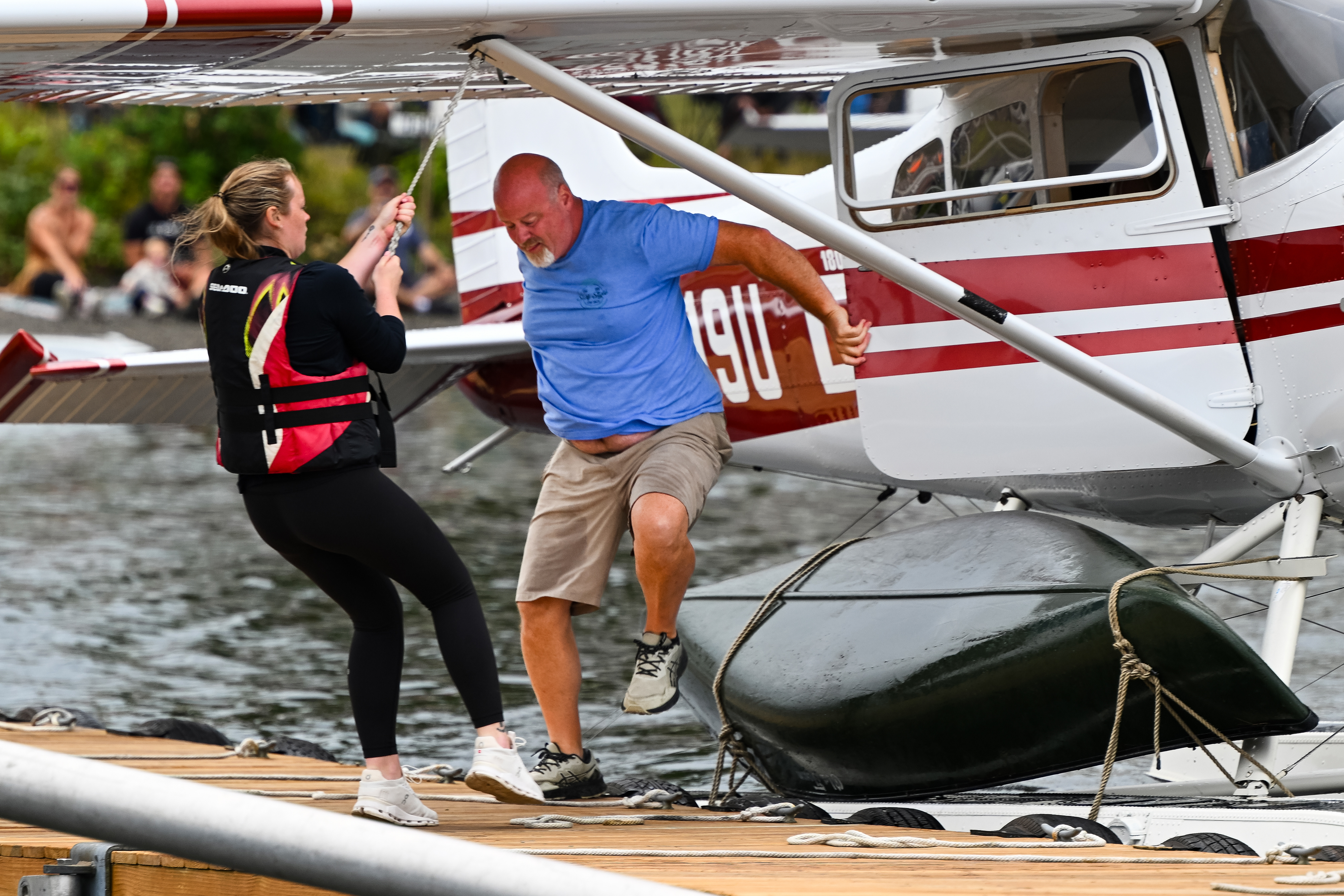 Baily Cust and her uncle, Jeff Hardy, scramble from his 1969 Cessna 180 floatplane to untie a canoe lashed to the aircraft. Photo by David Tulis.