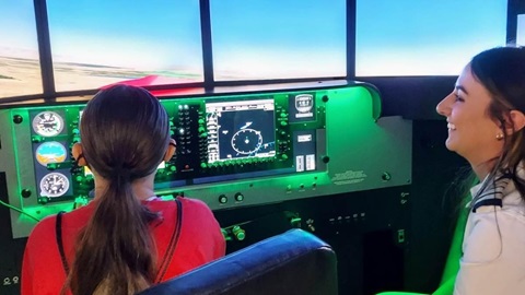 Olga helping a Young Marine experience flight in CAU's flight simulator.