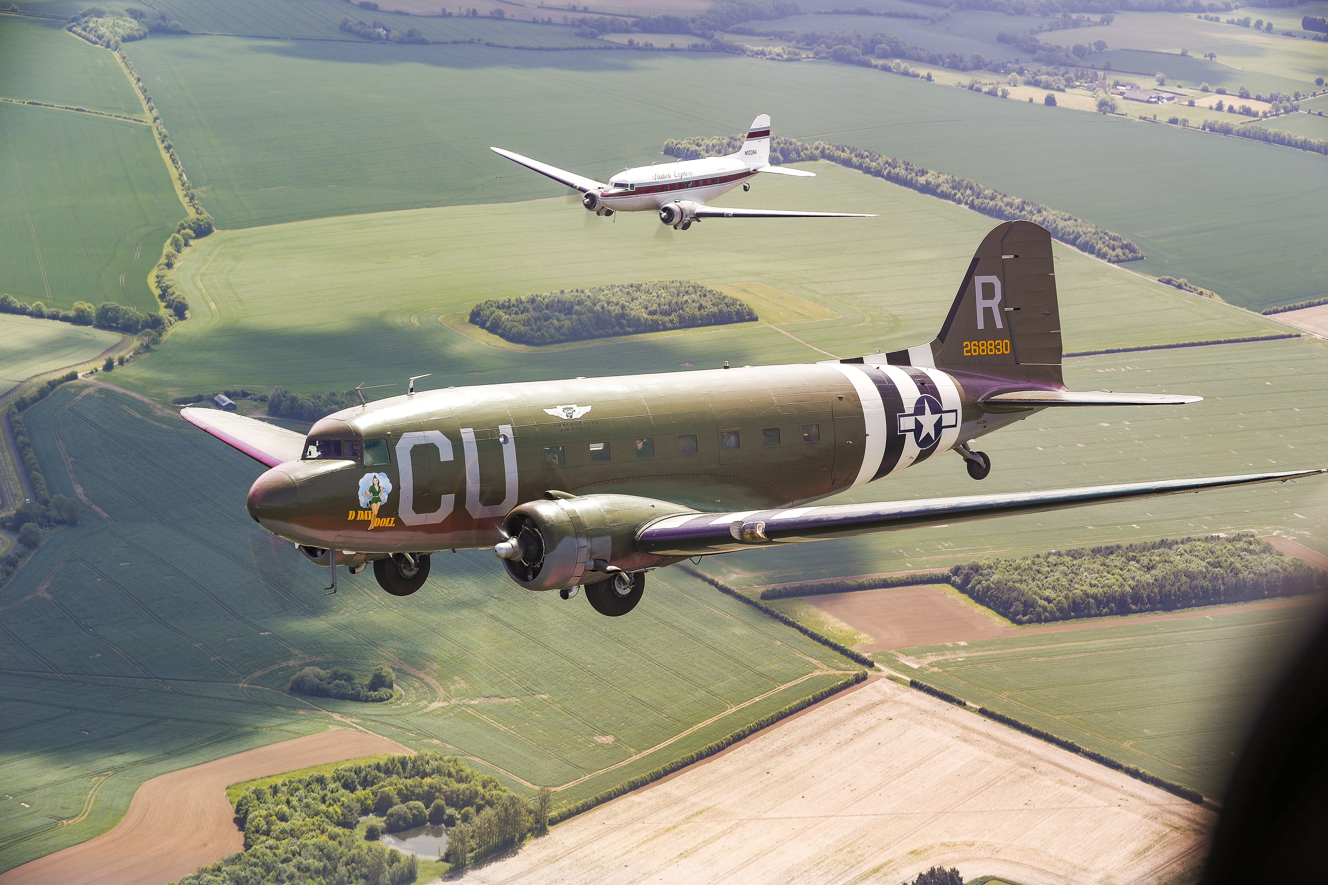 'D-Day Doll' and 'Flabob Express' form up during a practice flight over the English countryside.