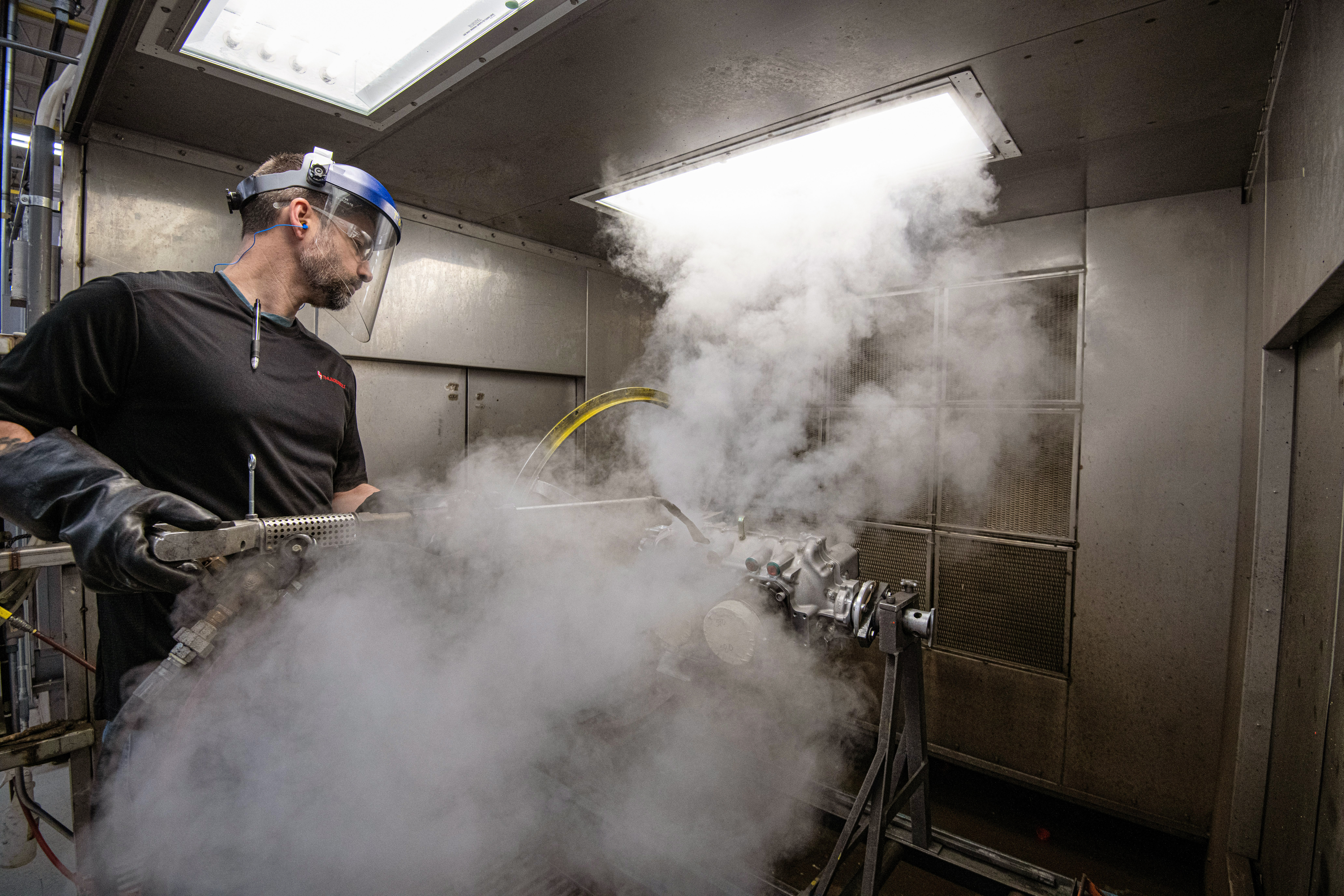 Paul Zener, who grew up working on his own cars and motorcycles, cleans the outside of an engine he helped build from the ground up.
