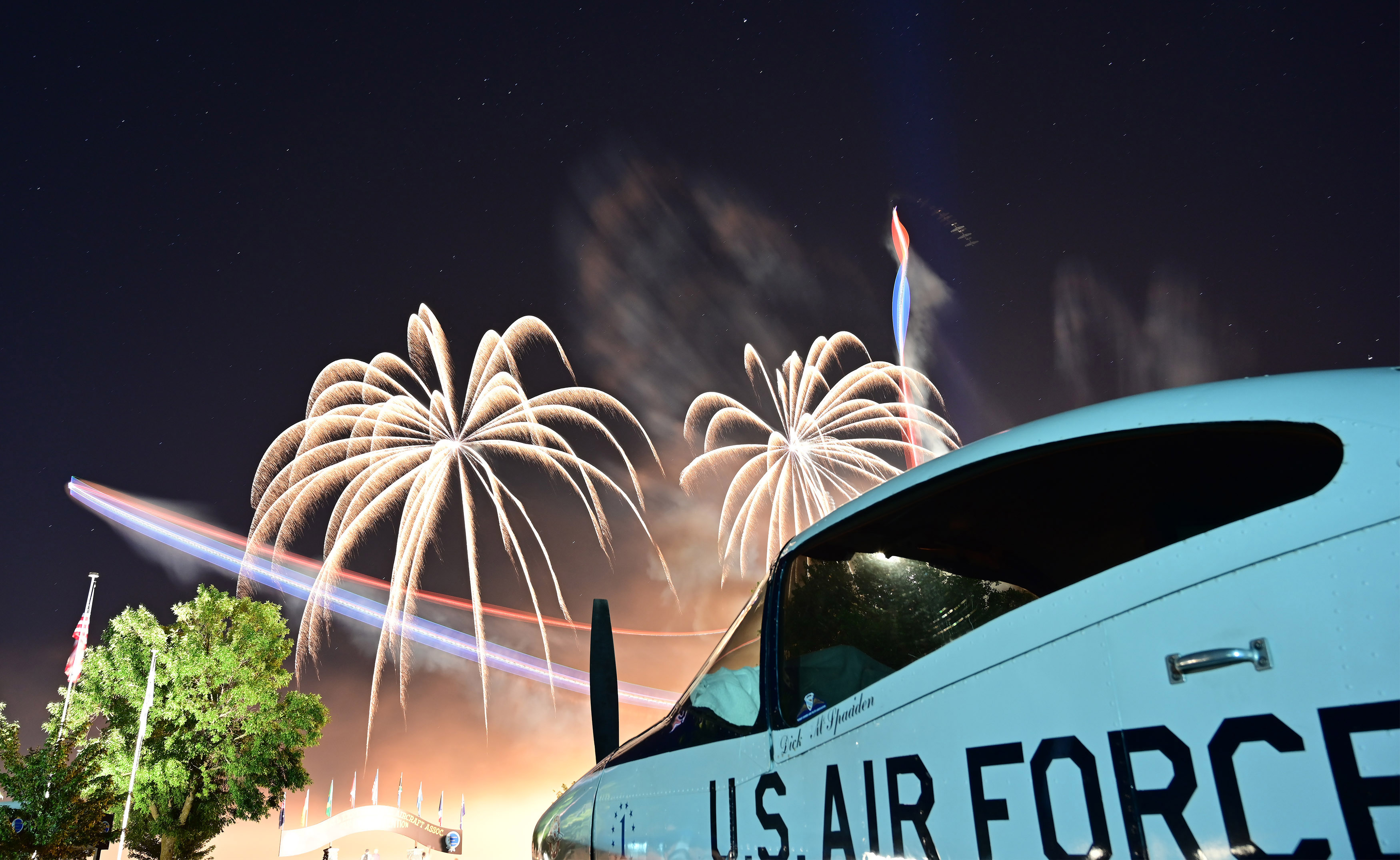 “AirVenture Highlighted by Celebration, Innovation,” July 29, 2019 aopa.org: Framed by a 1951 Ryan Navion B, the Twin Tigers Aerobatic Team lights up the sky to commemorate the fiftieth anniversary of EAA AirVenture at Wittman Regional Airport in 2019. Here, pilots Mark Nowosielski and Mark Sorenson sky dance above fireworks. (Nikon Z7, 24mm, 30, f5.6)