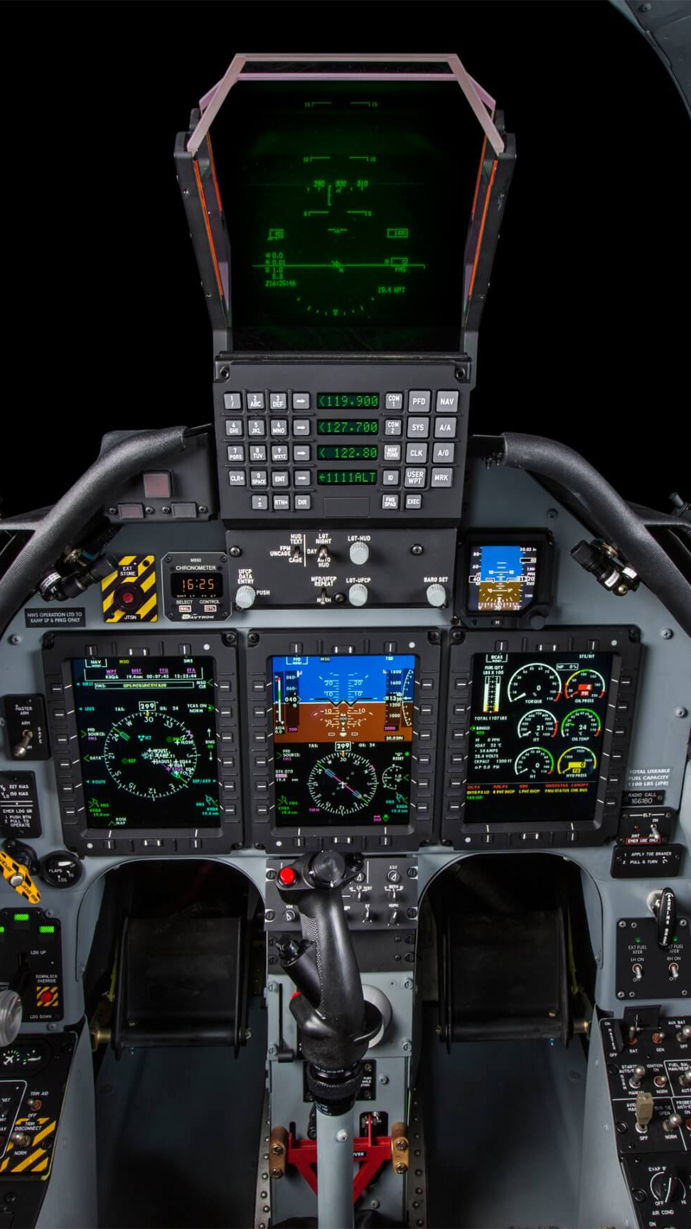 The T–6C cockpit has a HUD similar to those used in operational fighters, plus a three-screen Esterline display system. The weapons display is at the left, the PFD is in the center, and engine information is at the right. To jettison any wing-mounted hardware, press the red button surrounded by black and yellow stripes.