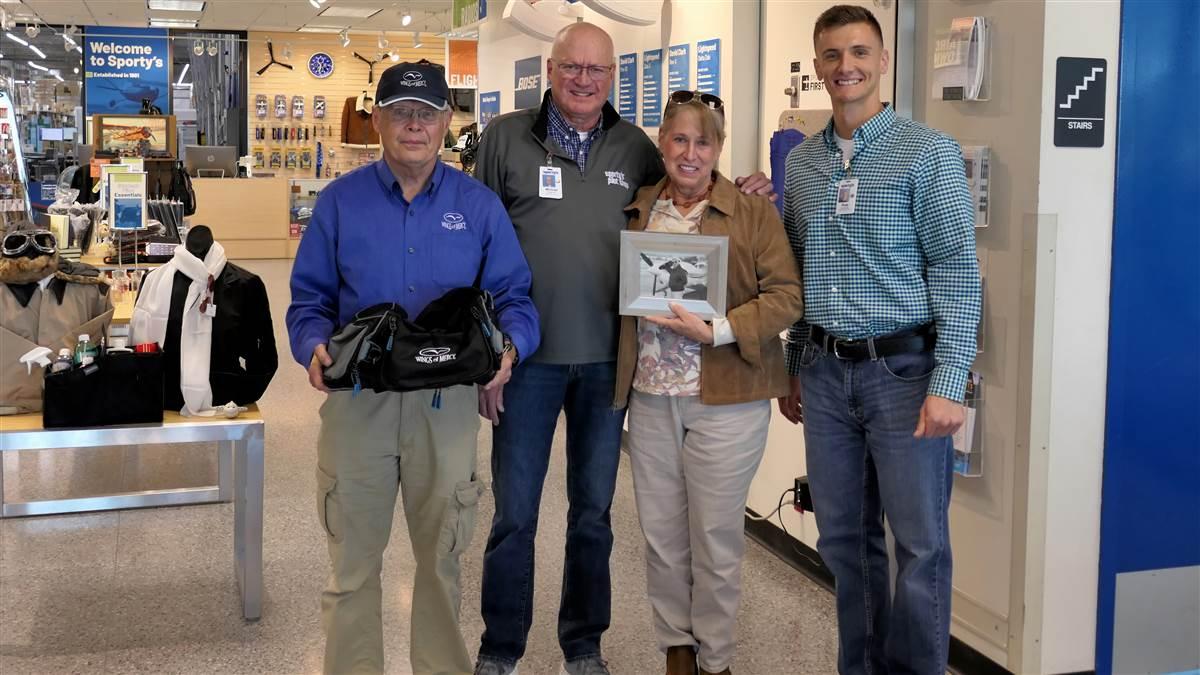 Left to right: Chuck Binder, Wings of Mercy Director of Operations; Michael Wolf, CEO Sporty’s Aviation; Judy Neiberg, holding picture of her husband Dr. Alan Neiberg in front of his Cessna 182; Russell Hartley, Special Assistant, Sporty’s.