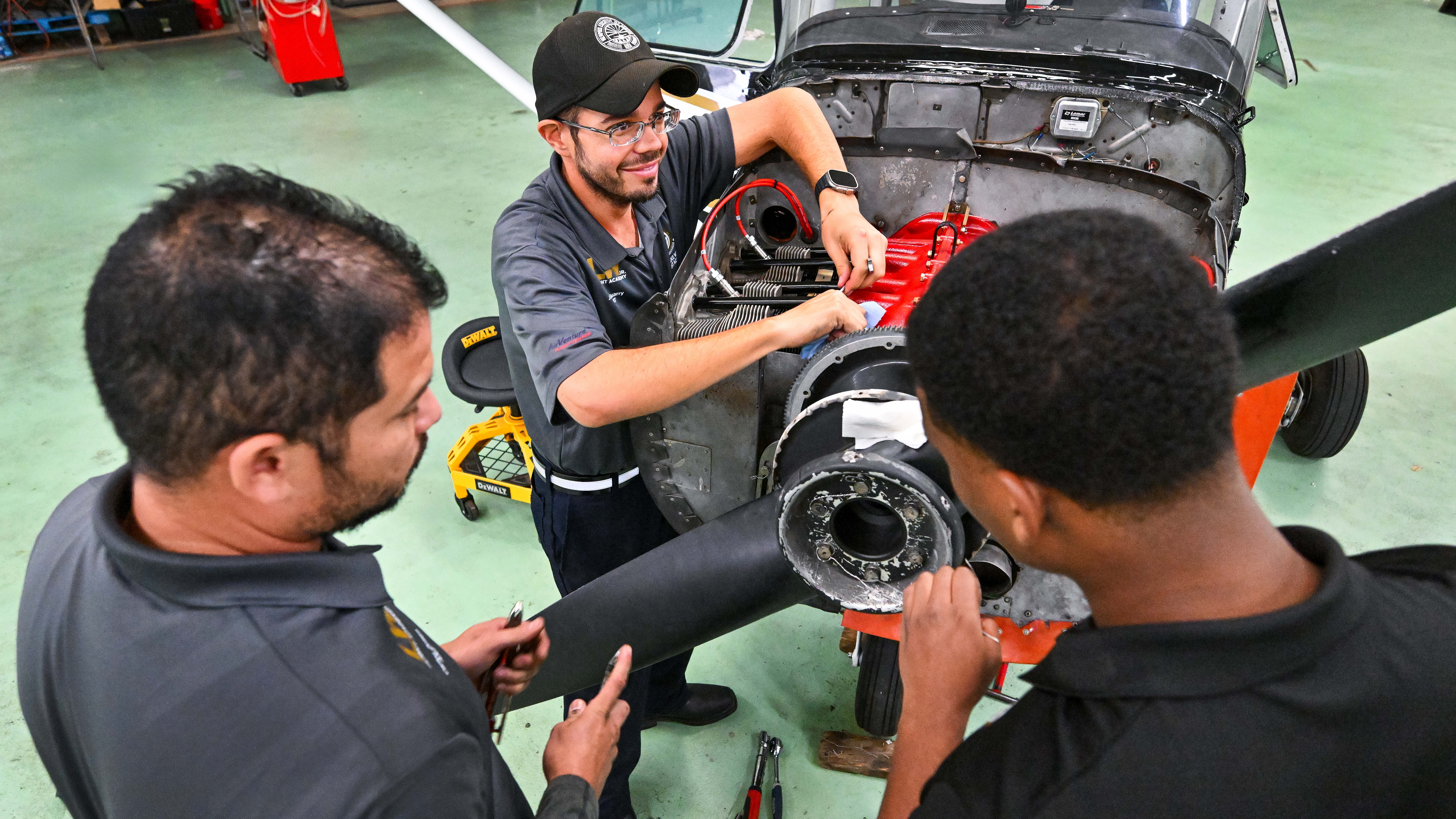It takes a village to run a flight academy. Aviation maintenance technician Jon Quarry (center) supervises final installation of a Pinnacle engine on an OBAP flight academy Cessna 172 with help from mechanic traines Carlos Zelaya (left) and Zach Girma.