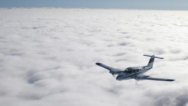 Twin engine airplane flying over a cloud layer