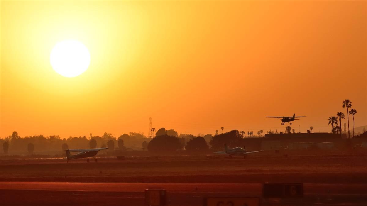 As the sun sets at Camarillo Airport on Friday night, a Cessna lands while two airplanes wait to depart. Photo by Mike Collins.