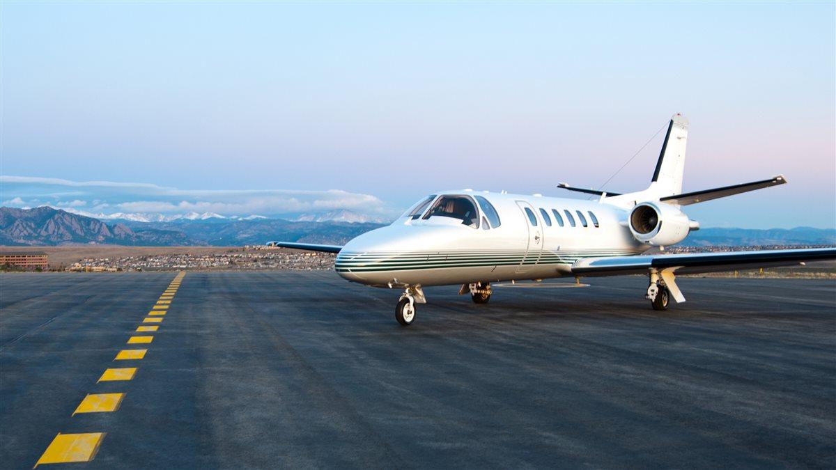 A Cessna Citation Bravo sitting at the end of ramp in the morning with the picturesque Rocky Mountains in the background.